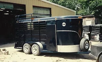 a black horse trailer is parked in front of a building