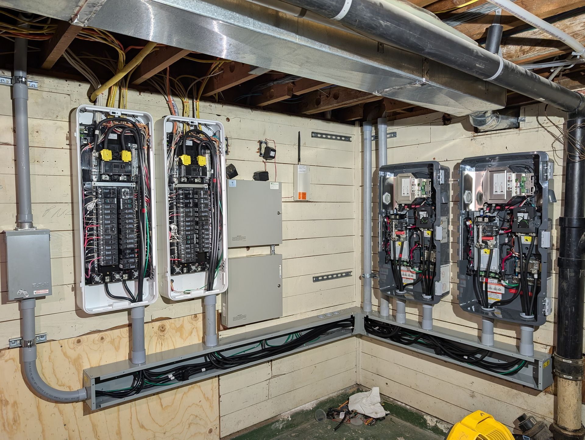 Open electrical control panels with wiring and breakers in a utility room.