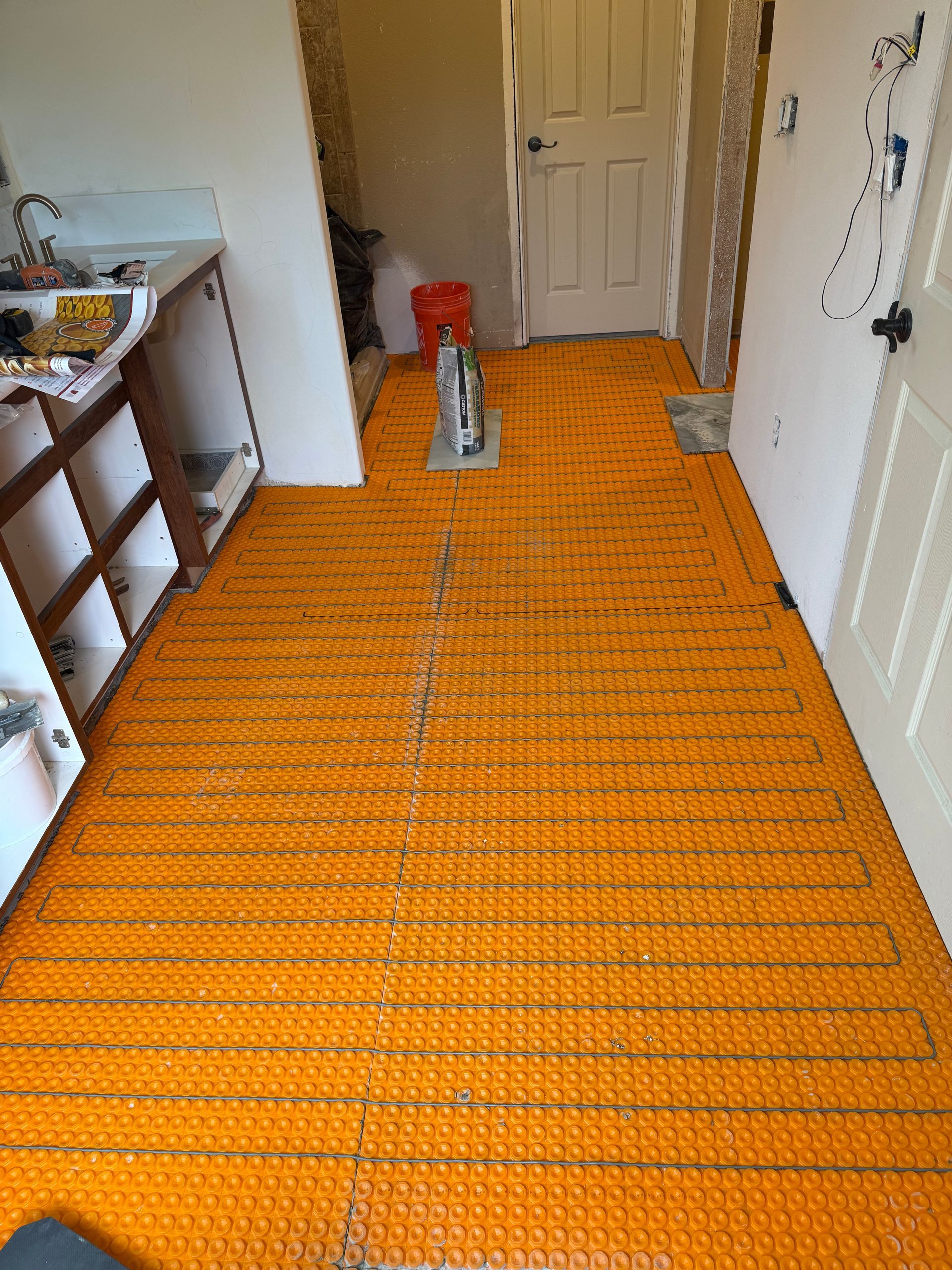 Orange protective floor covering in a hallway with a door and cleaning supplies.
