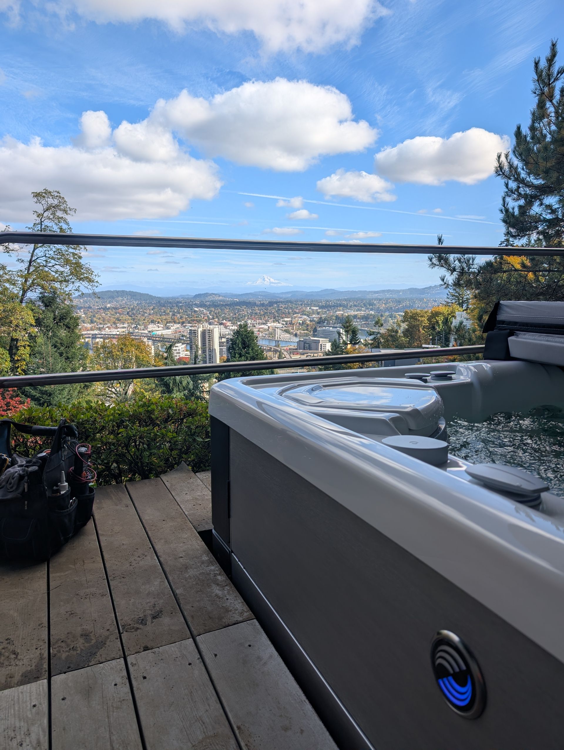 Backyard hot tub on a deck with city and mountain views under a partly cloudy sky