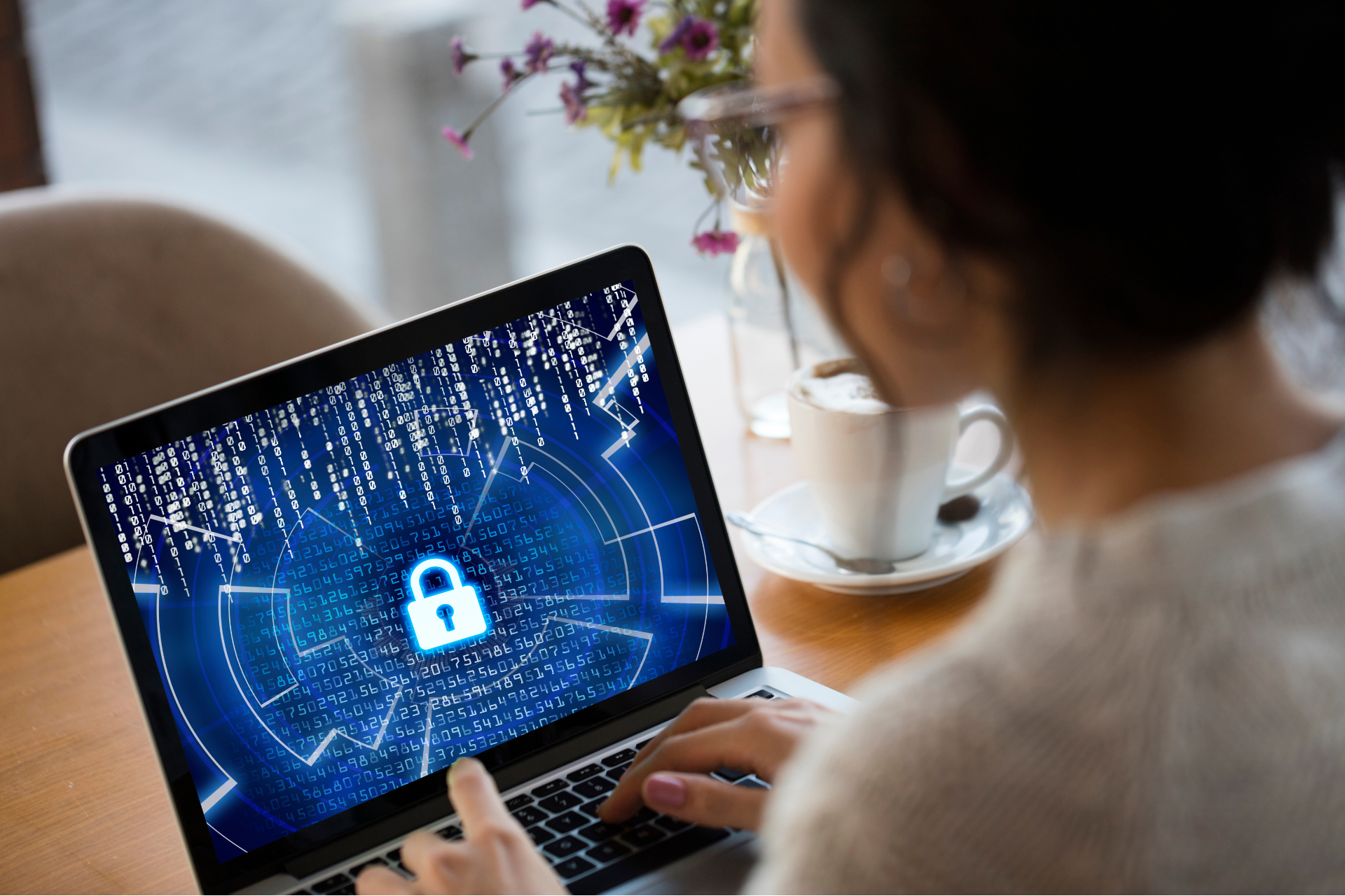 Woman using laptop with security lock screen in a cafe.