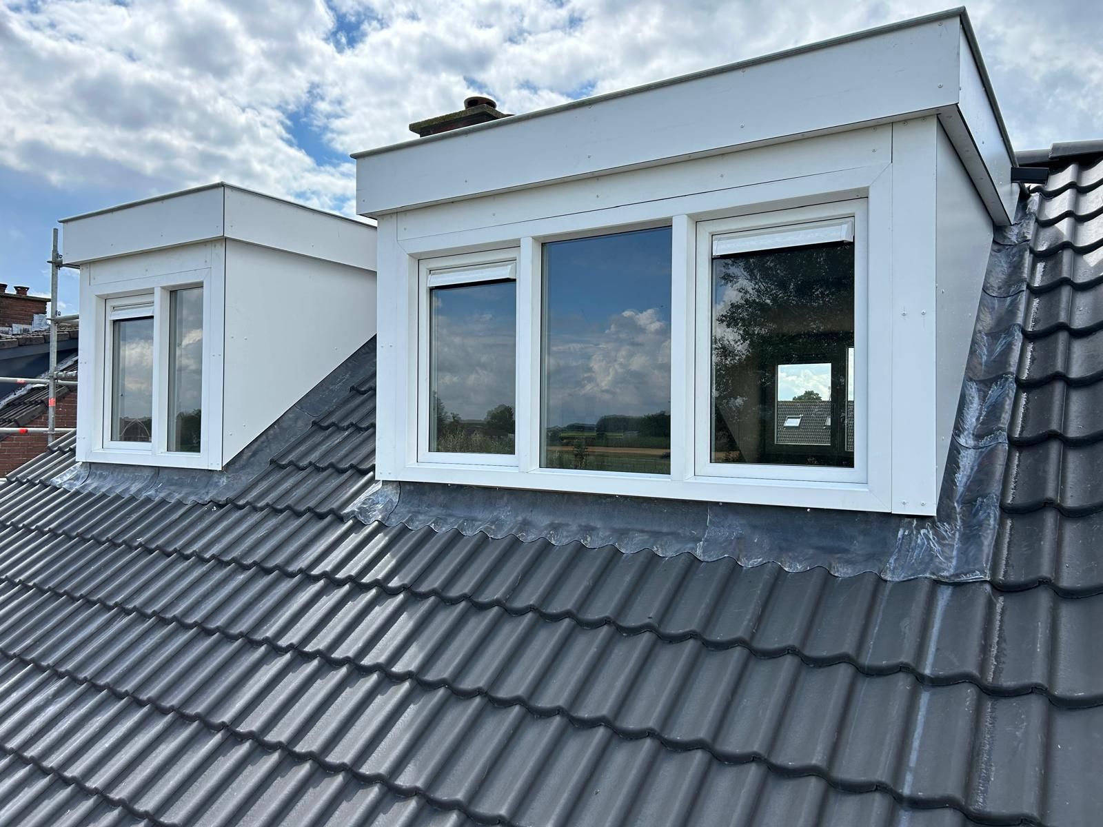 Witte dakopbouw met ramen. Moderne dakuitbouw bij huisrenovatie.
