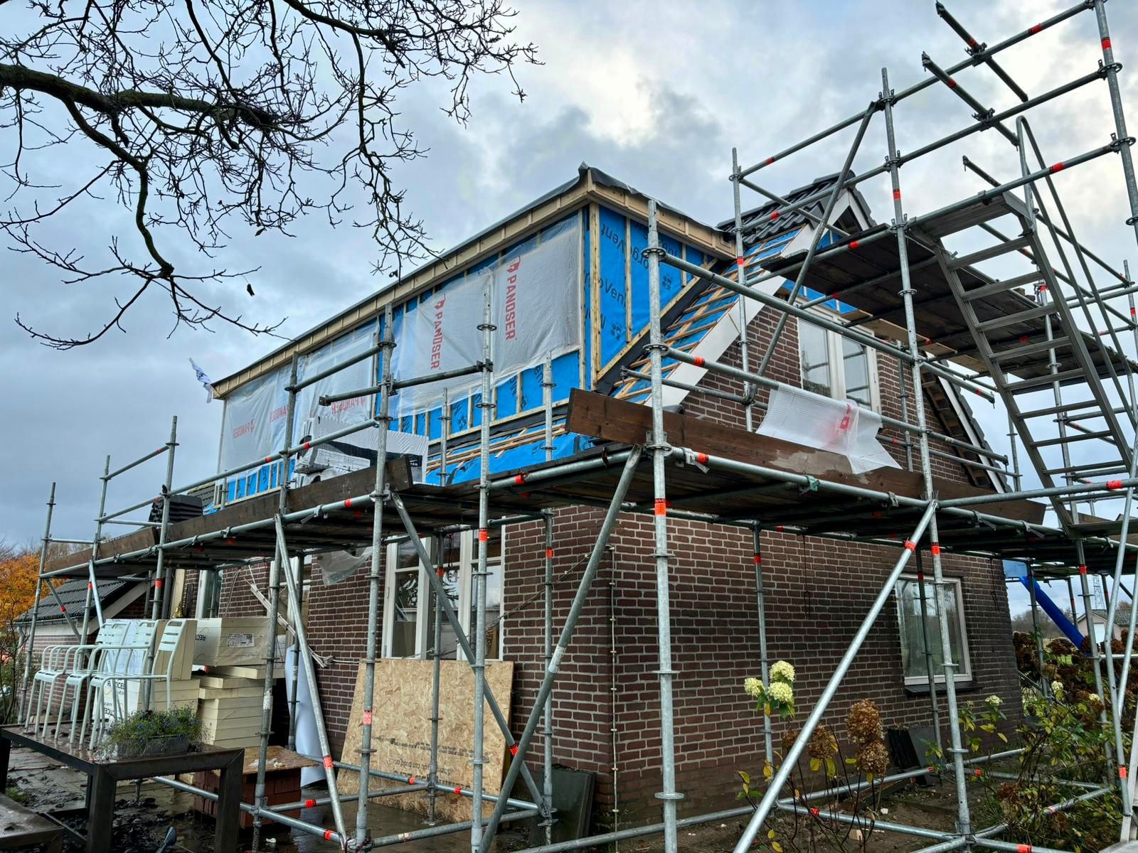 Bakstenen woning in renovatie met beschermde dakwerk. Dakrenovatie en woningrenovatie.