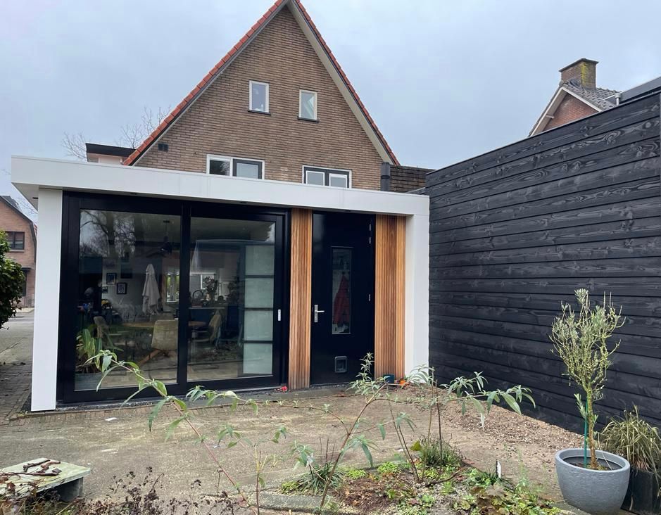Baksteenhuis grote glazen deuren wit frame. Renovatie uitbouw modern raamwerk.