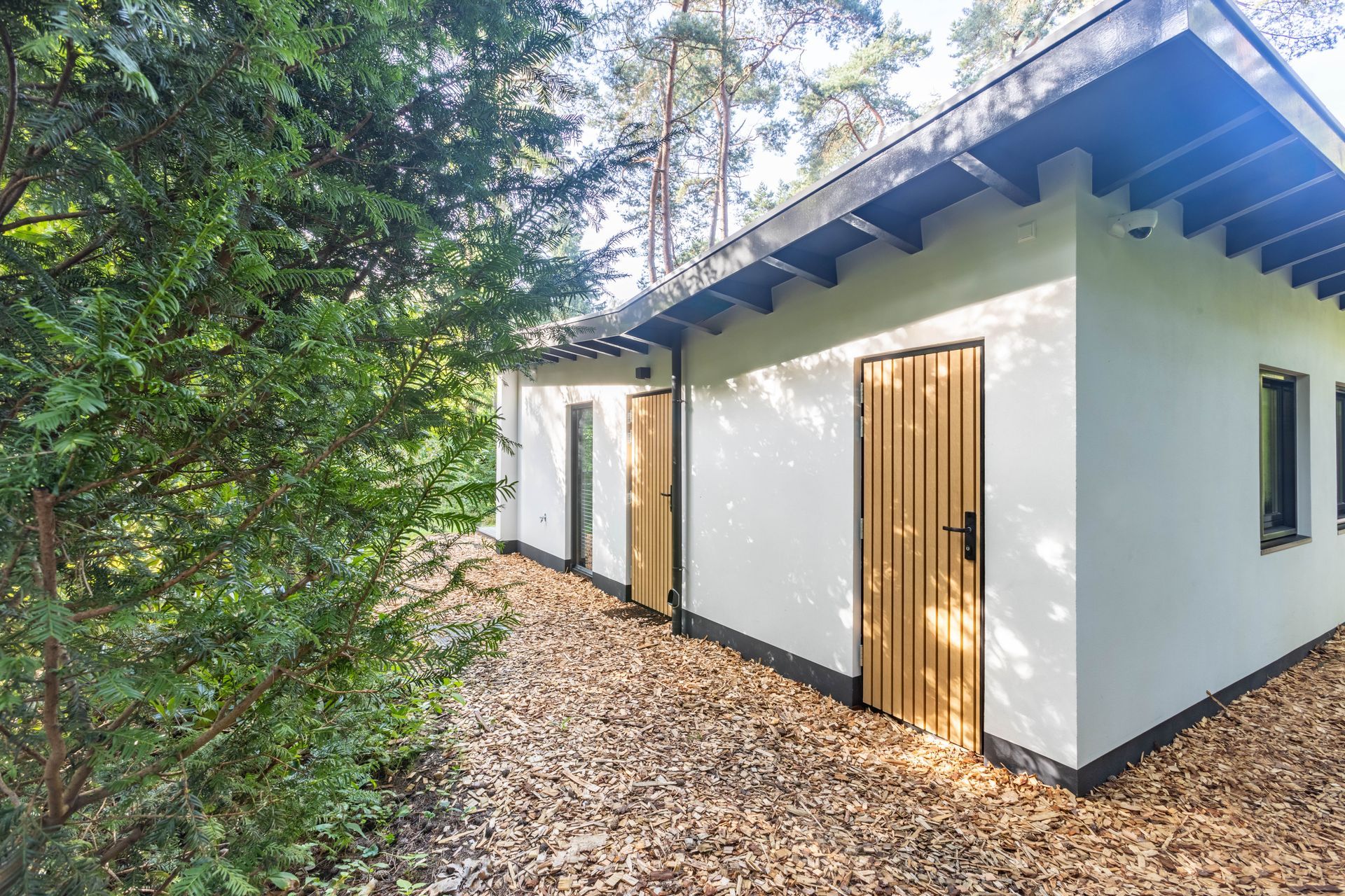 witte aanbouw tuinzijde. Blauwe dakrand gevelkozijn. Verbouwing woning.