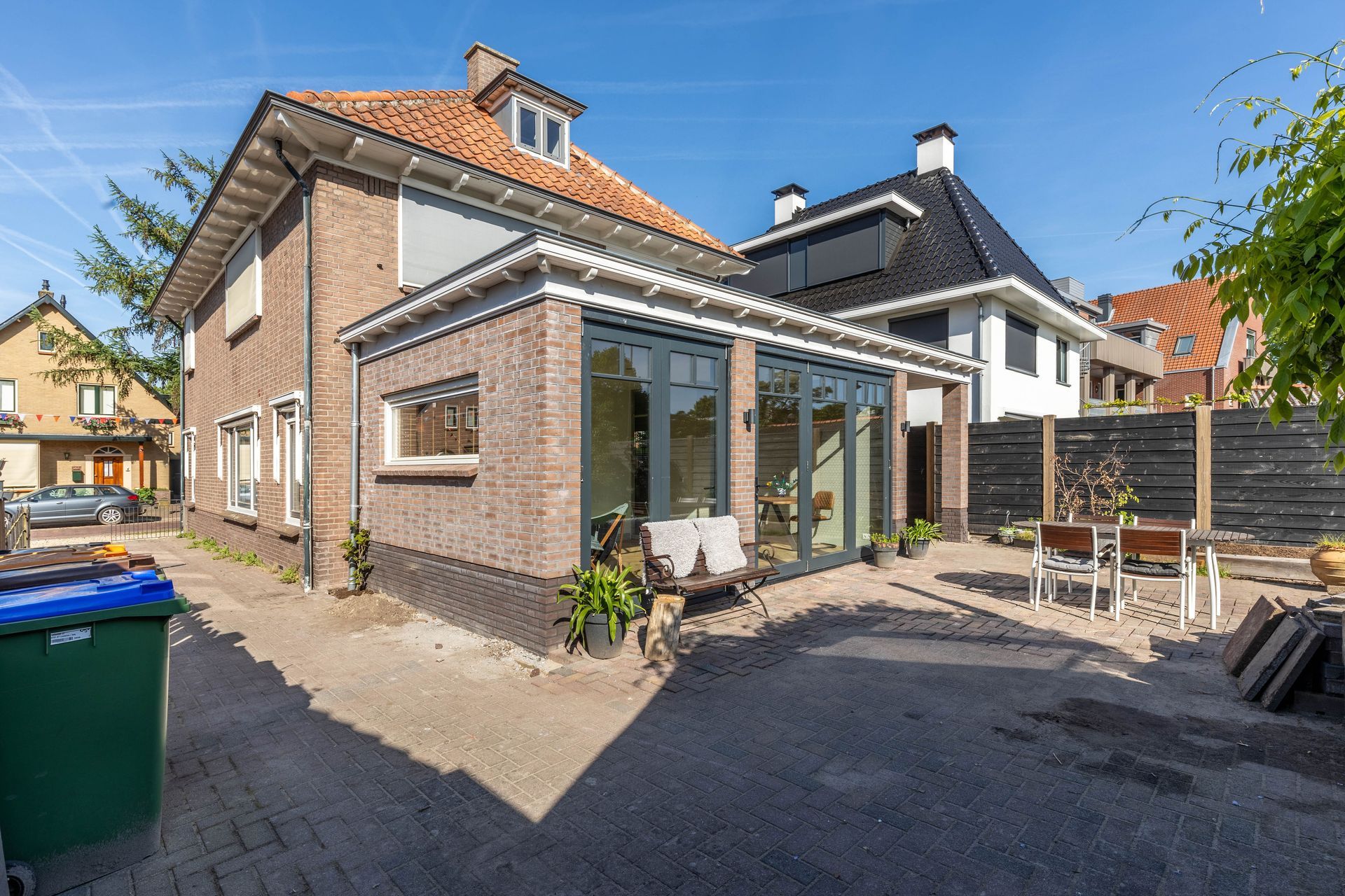 Bakstenen woning moderne aanbouw. Glas schuifdeuren verbouwing. Uitbouw renovatie.