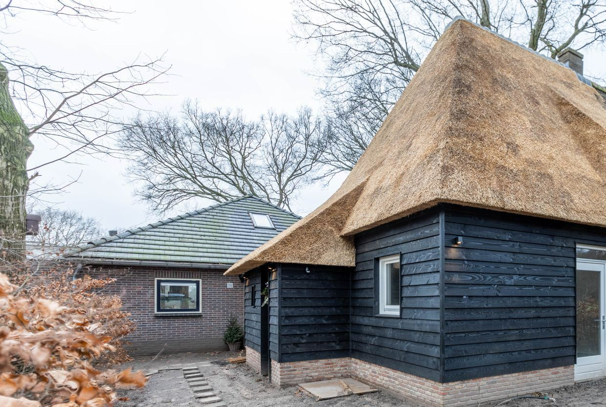 Rieten dak op houten gebouw. Traditionele dakbedekking bij renovatie. Houtwerk en riet.