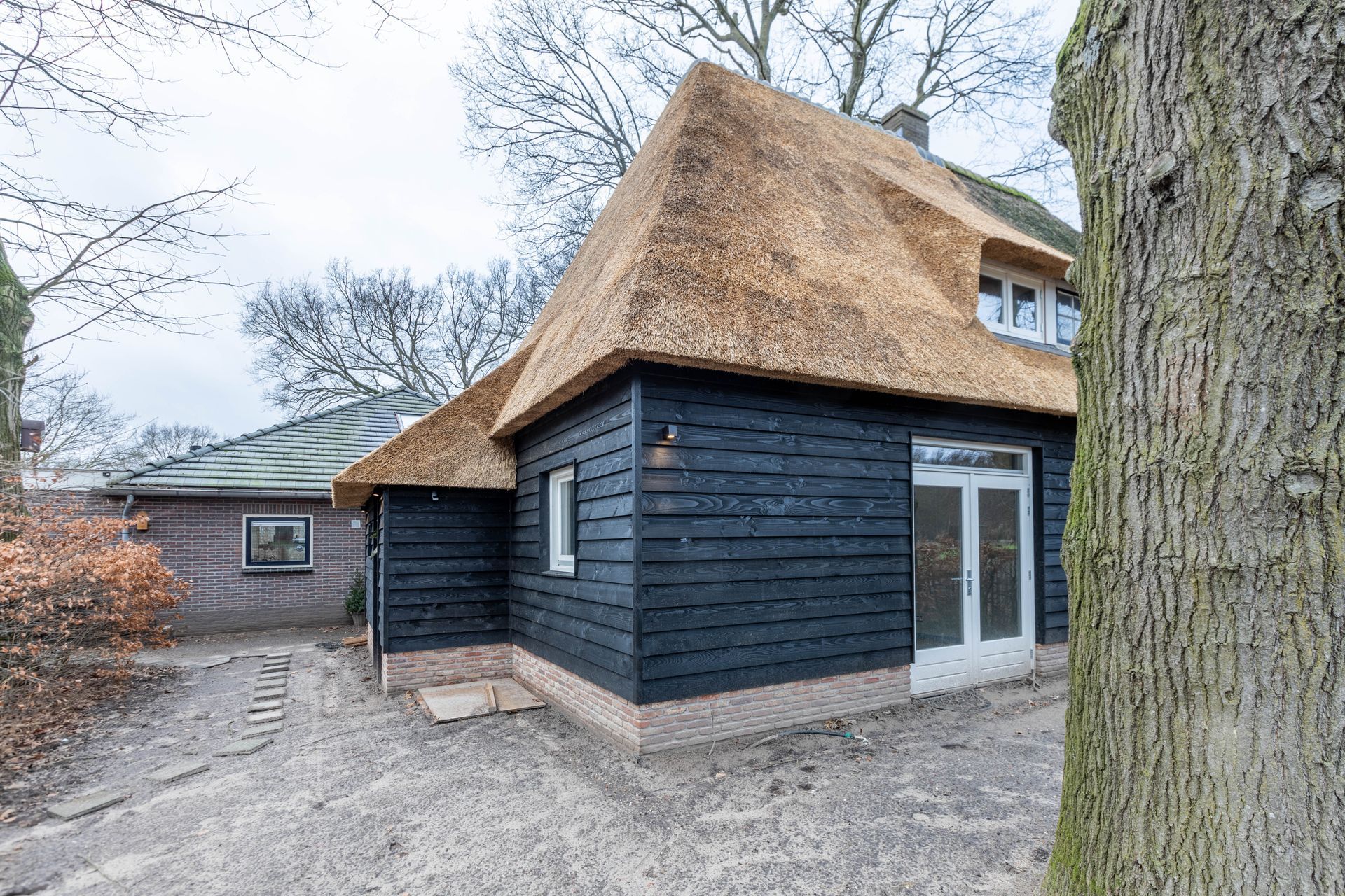 Rietgedekt huisje volledig. Donkere houten schuur met rieten dak. Traditionele dakbedekking.