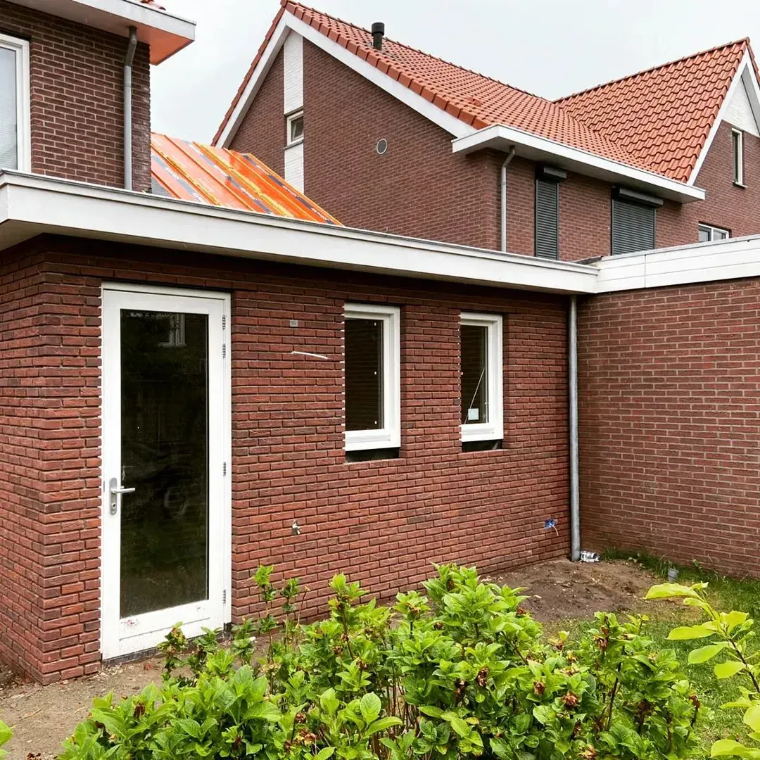 Bakstenen huis met terracotta dak. Aanbouw gevel renovatie.