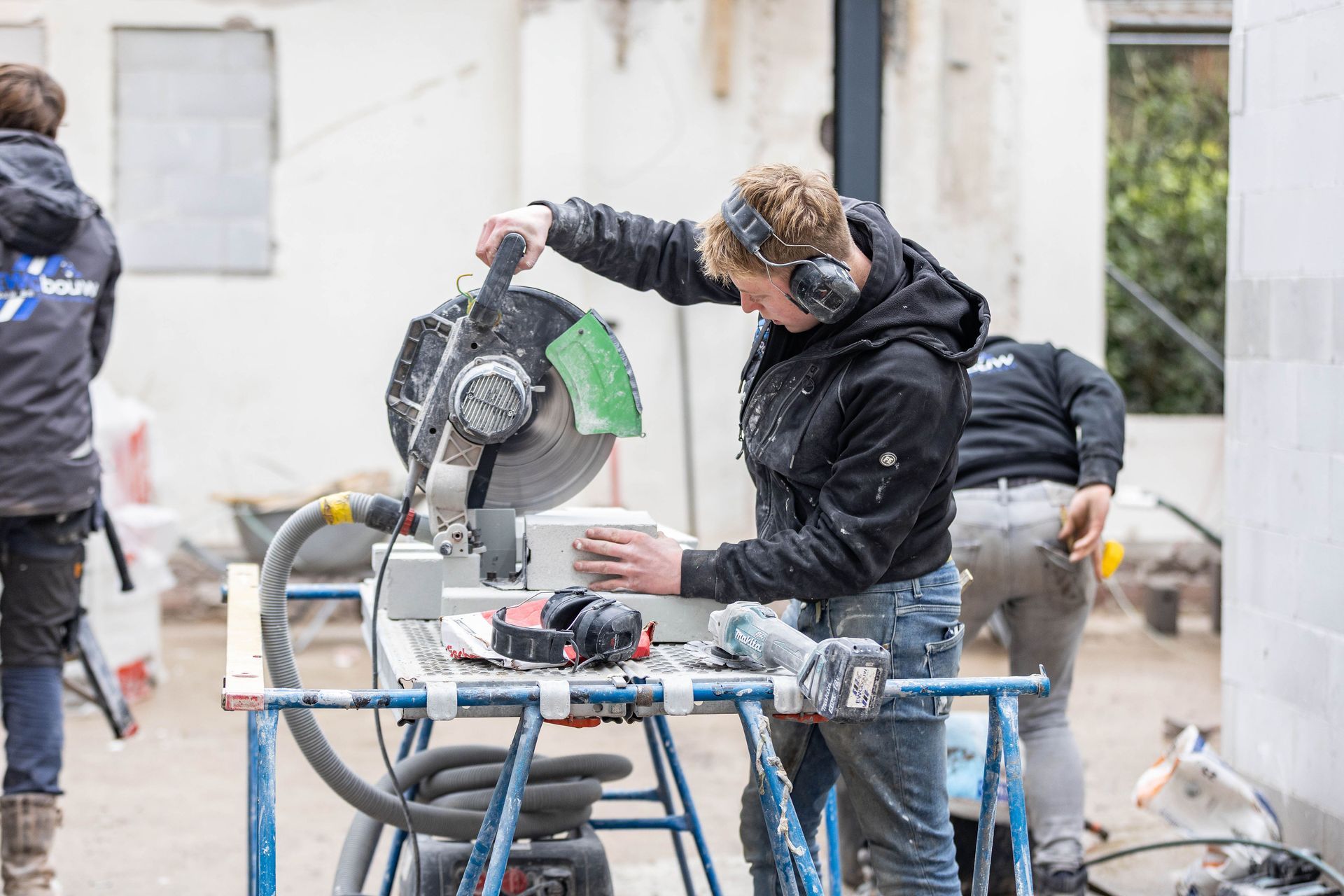 Aannemer aan het werk met afkortzaag tijdens renovatie – verbouwing woning Doorn door EWG Bouw
