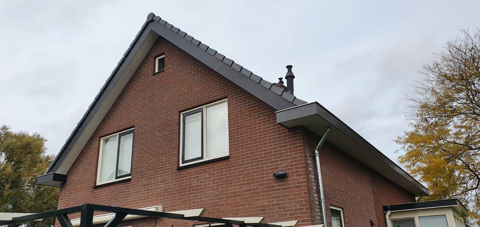 Bakstenen woning met modern zwart dak. Dakrenovatie en woningrenovatie.