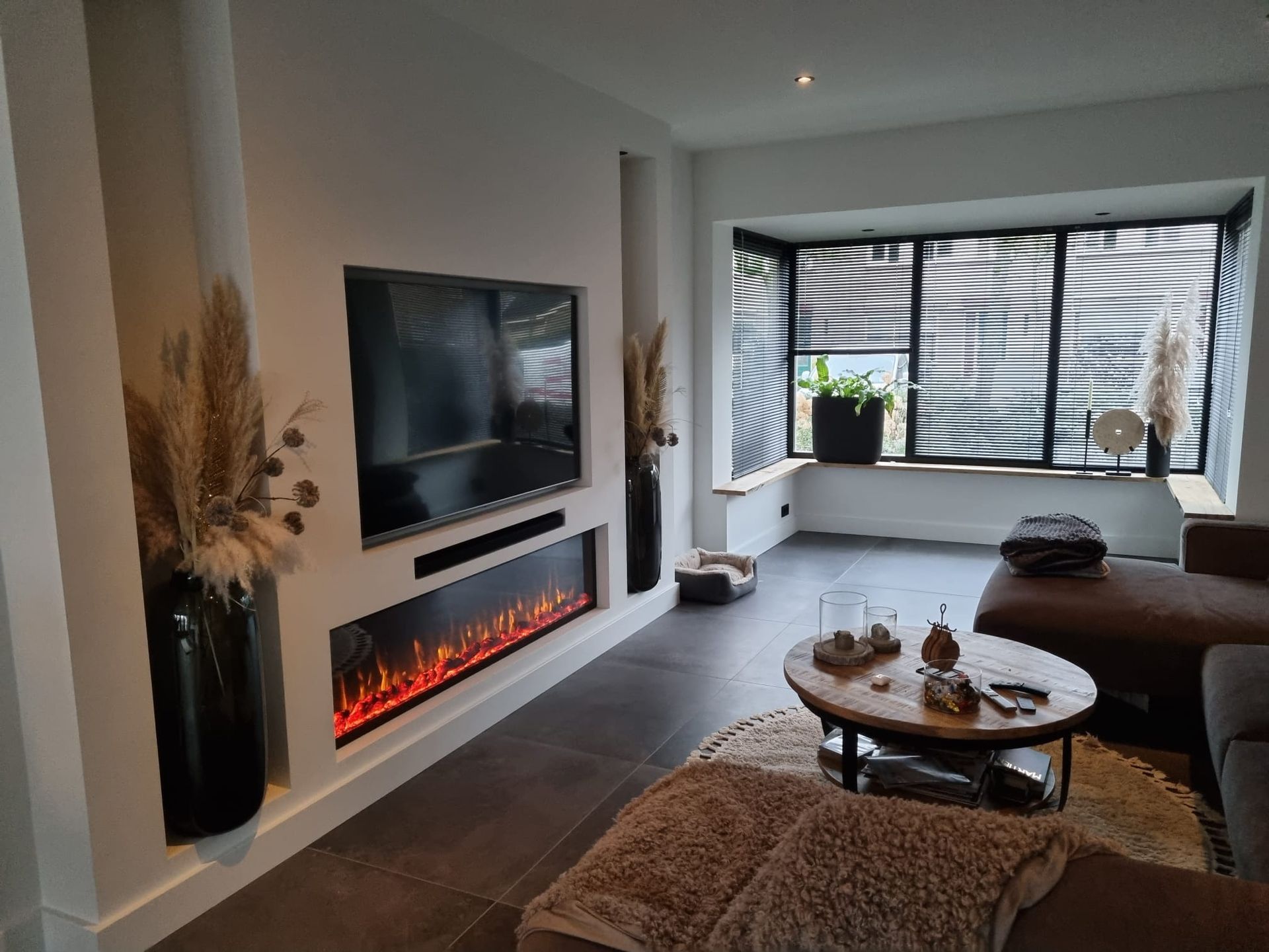 Gerenoveerde woonkamer met ingebouwde elektrische haard. Interieur verbouwing en woonruimte renovatie.