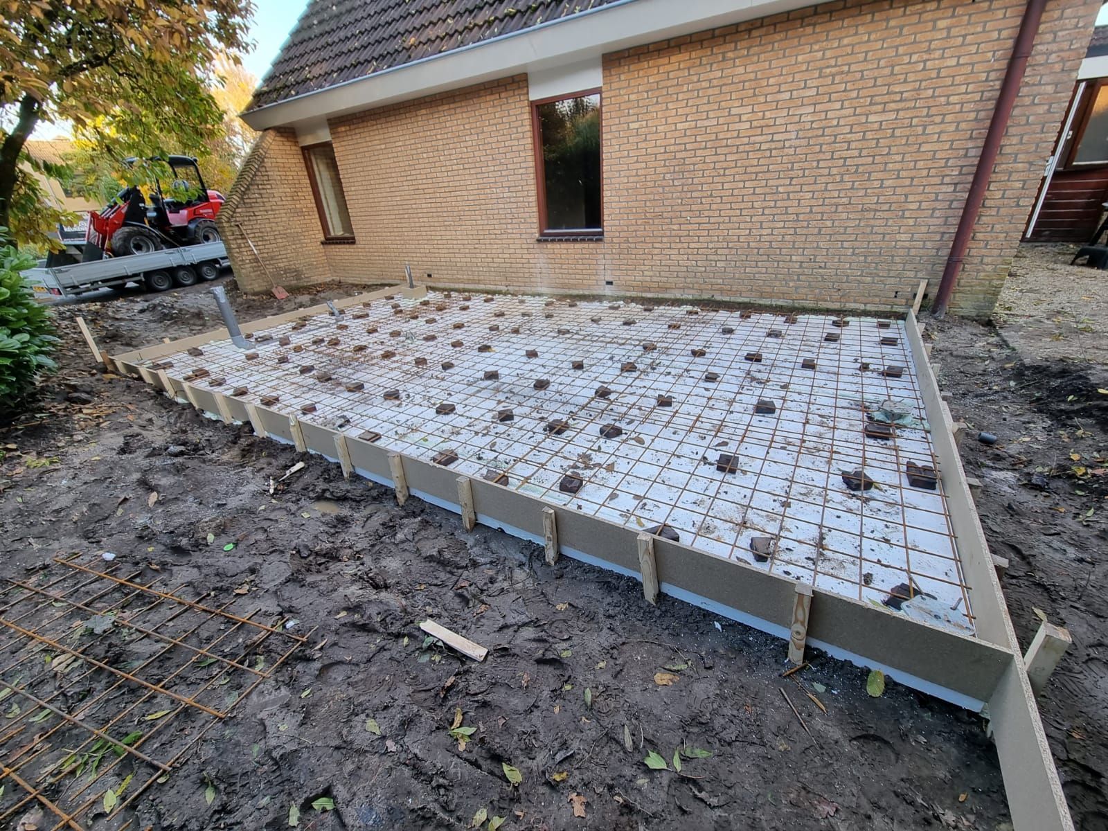Terras tegels leggen. Bakstenen woning met terrasafwerking in aanbouw.