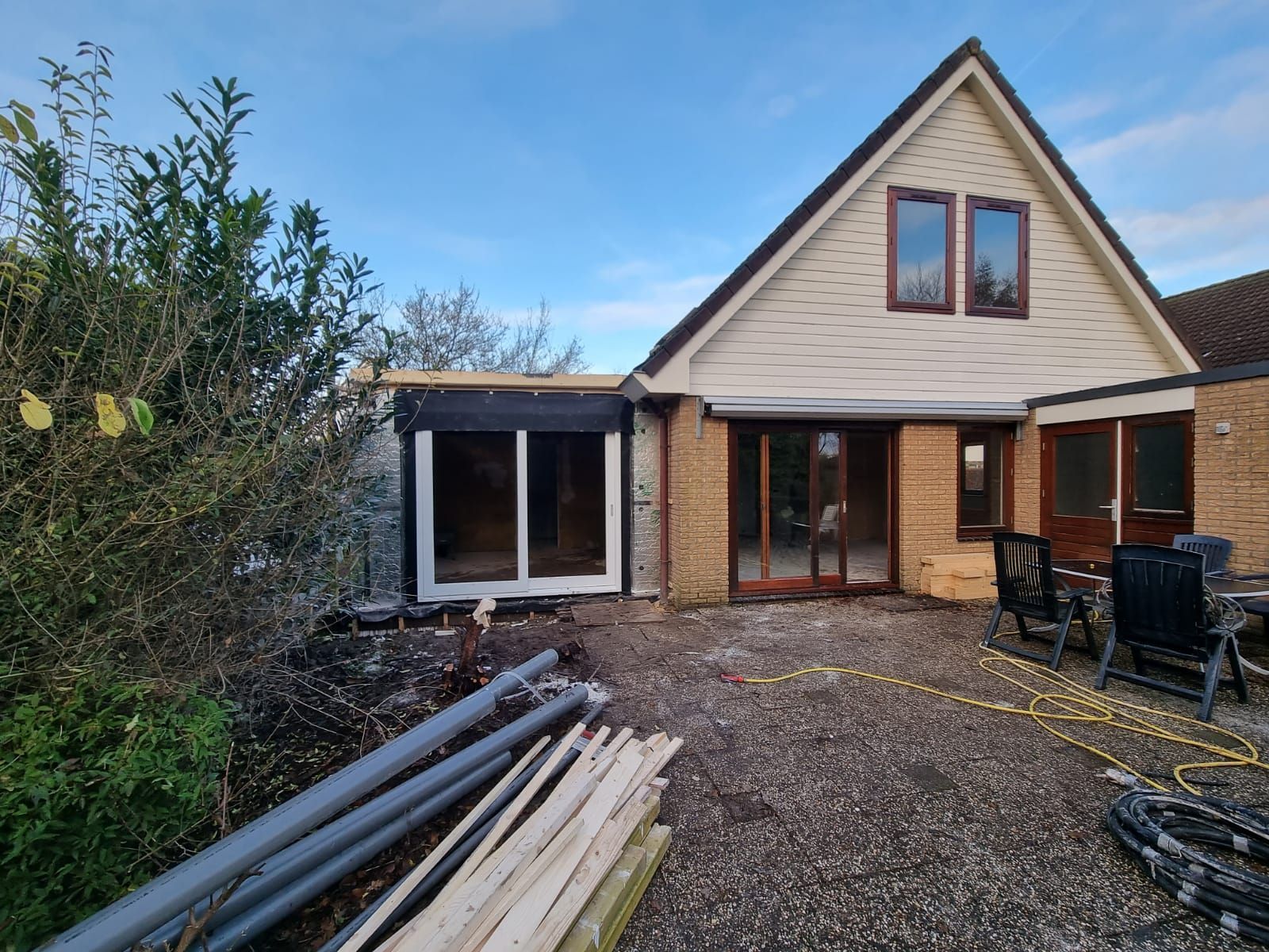 Witte veranda uitbouw aanleg. Moderne verbouwing van woonhuis. Uitbreidingswerk in aanbouw.