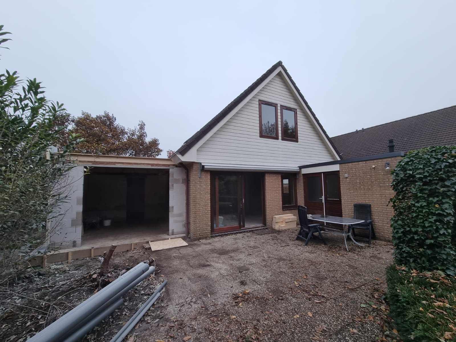 Veranda uitbouw gestart. Houten en bakstenen woning met nieuwe veranda aanbouw.