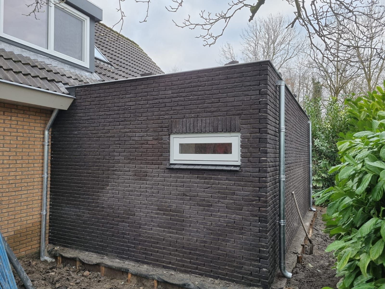 Donkere bakstenen aanbouw aan woning. Moderne aanbouw en verbouwing renovatie.