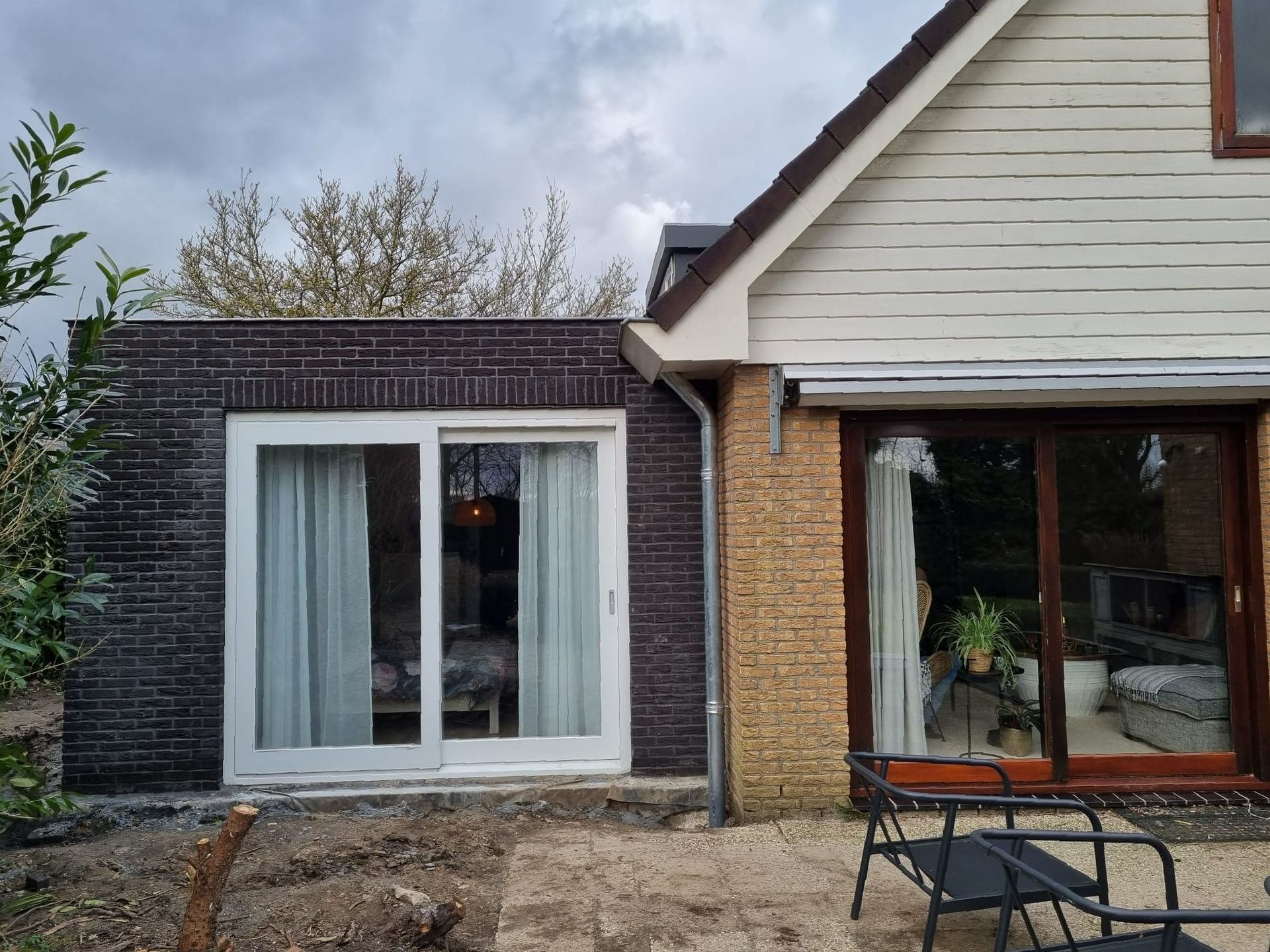 Moderne zwarte aanbouw met grote ramen. Verbouwing woning en uitbouw aanbouw.