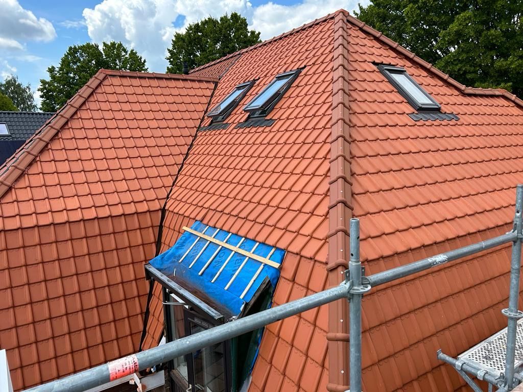  Dak met dakramen en zonnepanelen. Rode dakpannen met blauwe onderdelen. Dak renovatie.