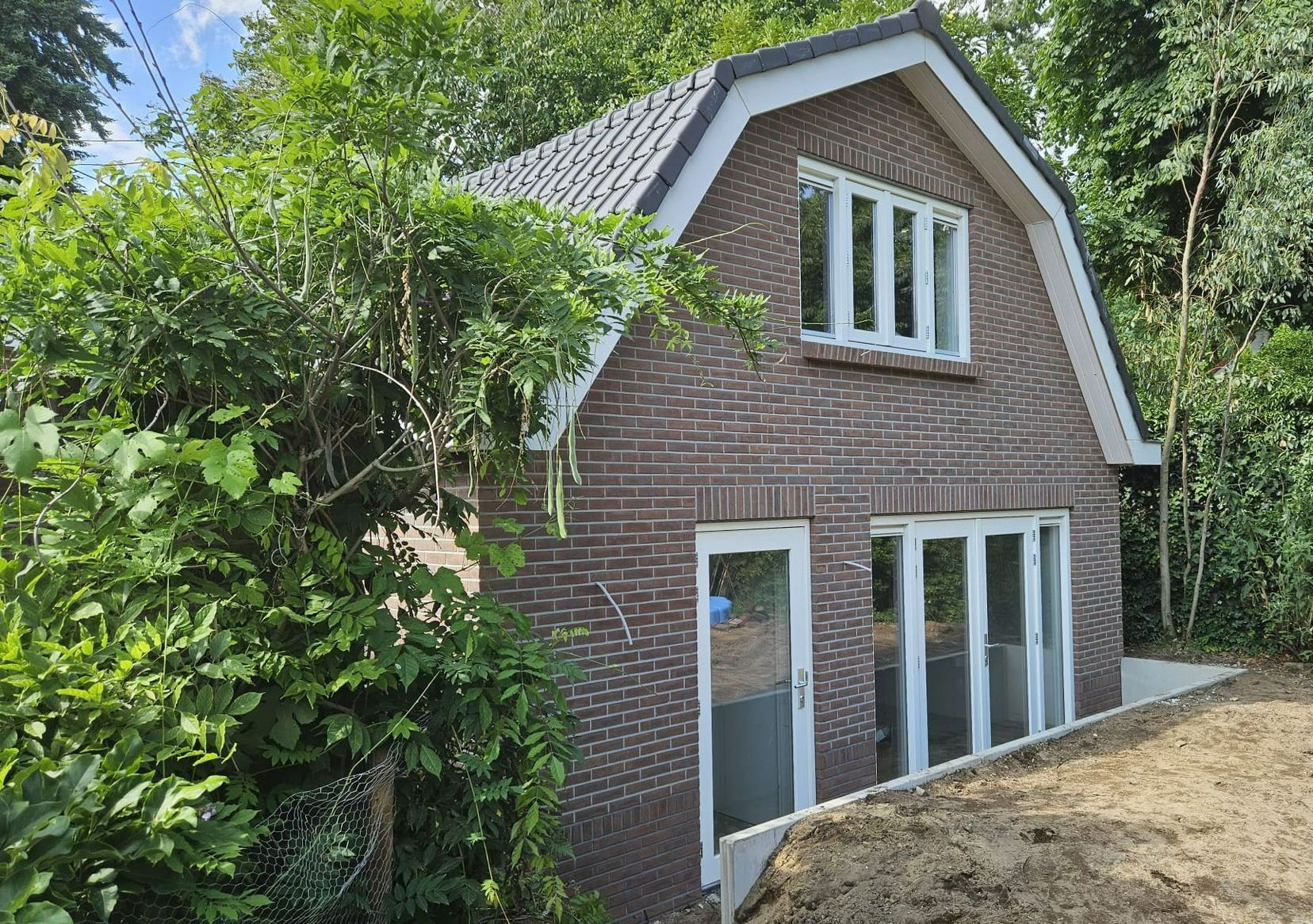 Gerenoveerde bakstenen woning. Kleine houten aanbouw. Eigentijdse verbouwing huis.