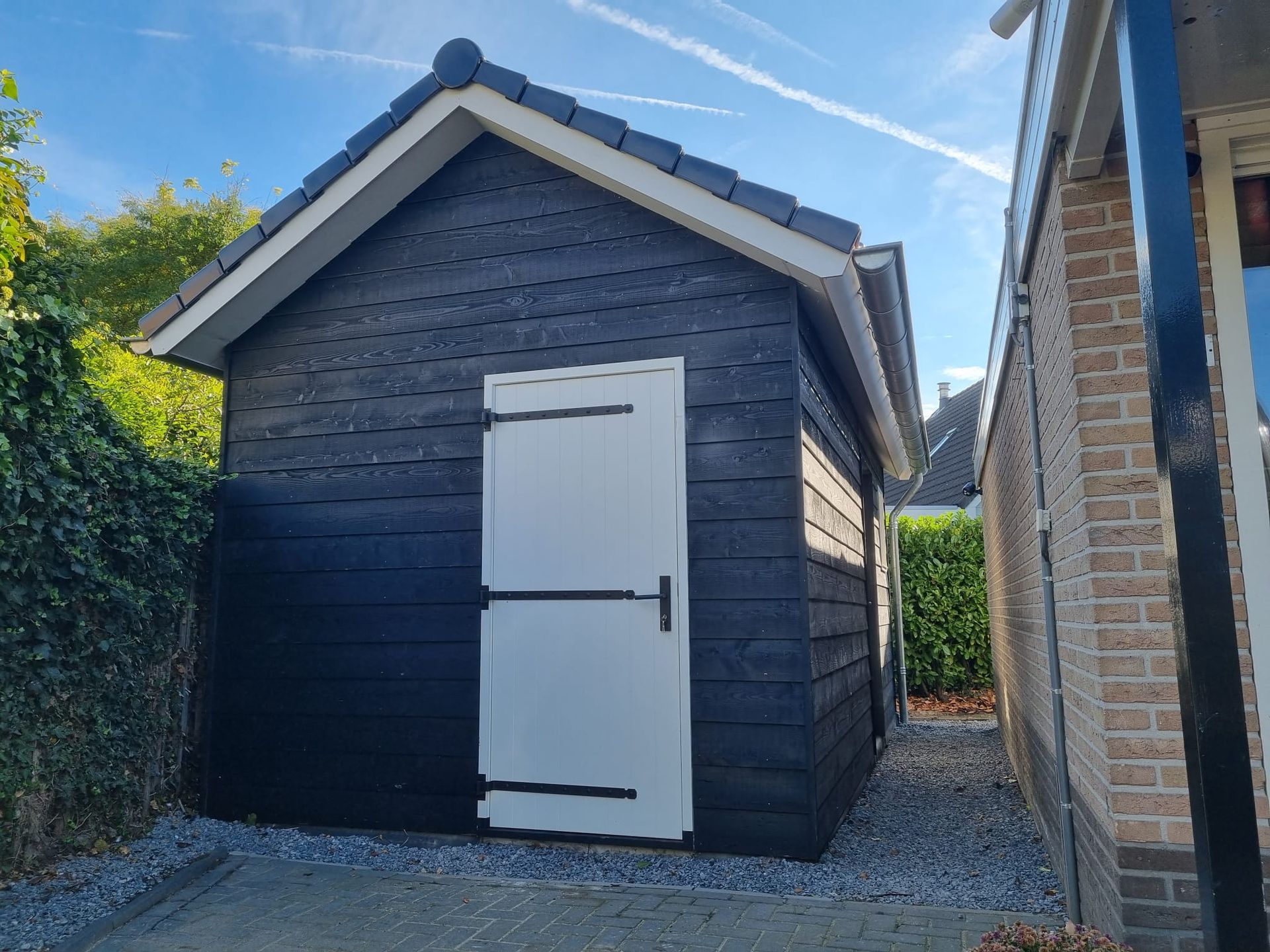 Tuinhuis renovatie. Houten wanden grijs wit dak. Tuin aanbouw.
