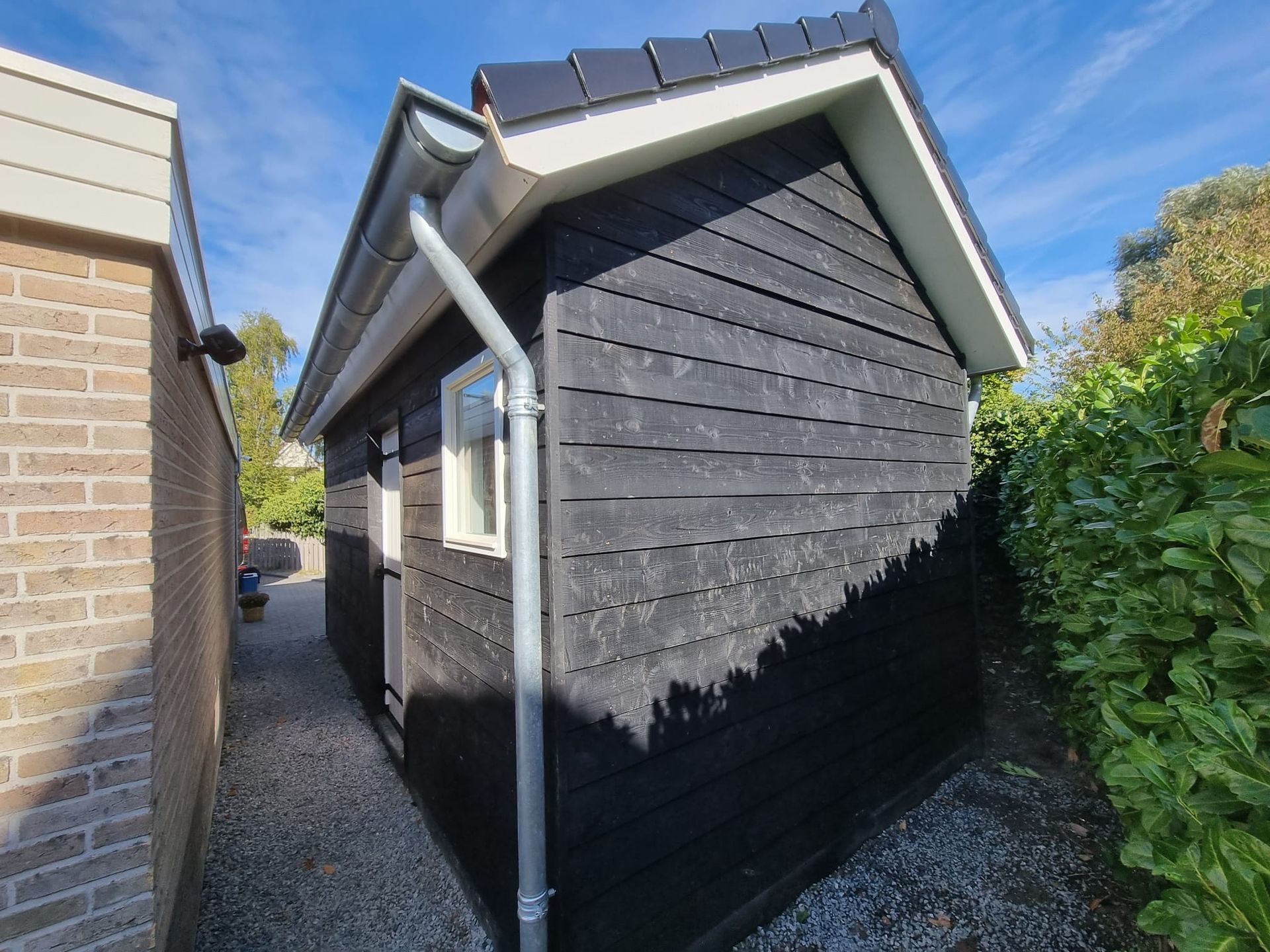 Bijgebouw verbouwing donker houtwerk. Tuinhuis renovatie modern
