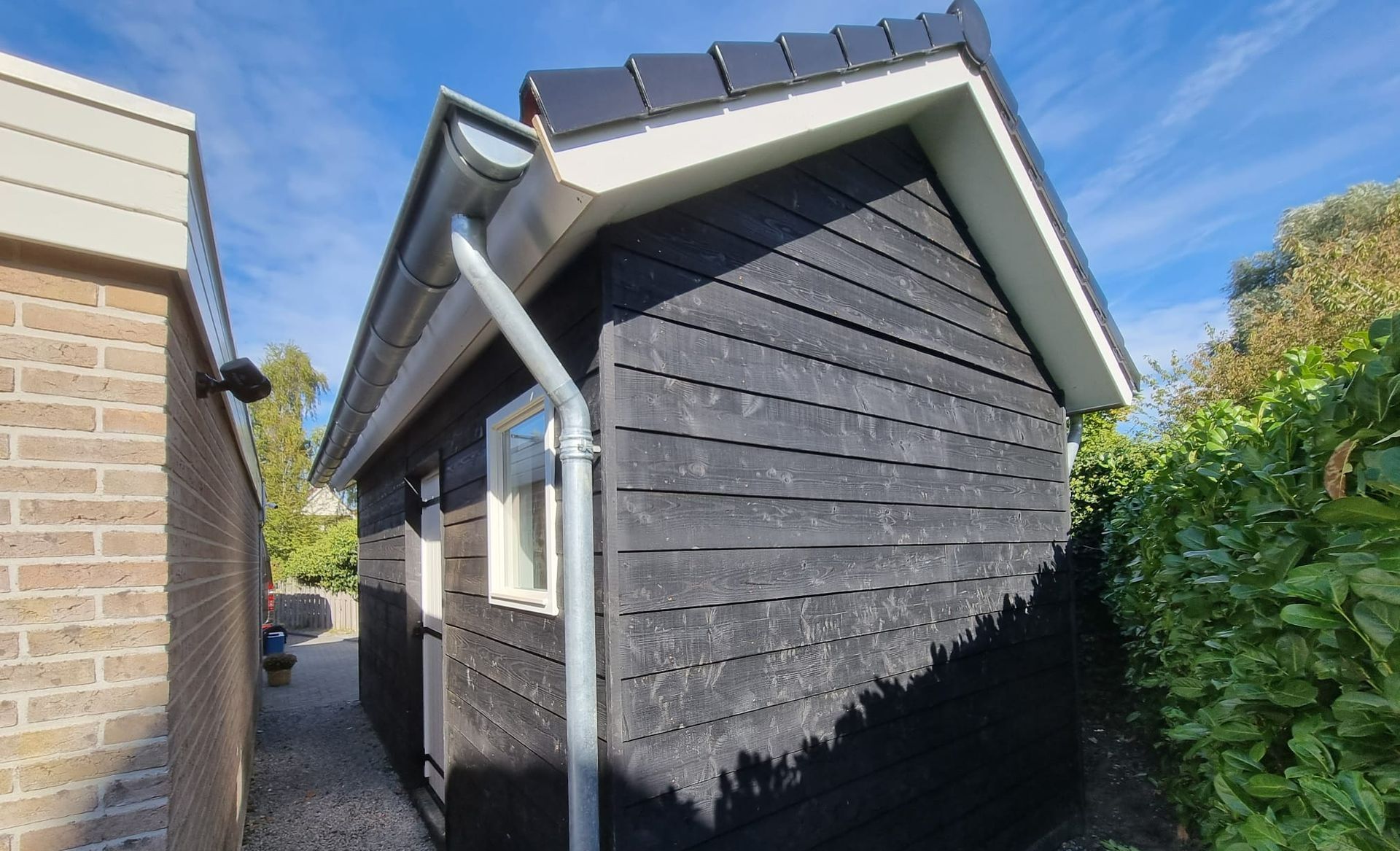 Tuinhuis met dak. Houten schuur grijs. Aanbouw tuin renovatie.