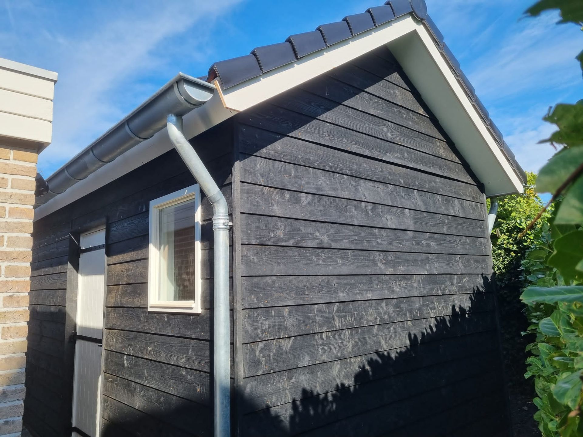 Bijgebouwverbouwing donker hout. Tuinhuis aanbouw modern design