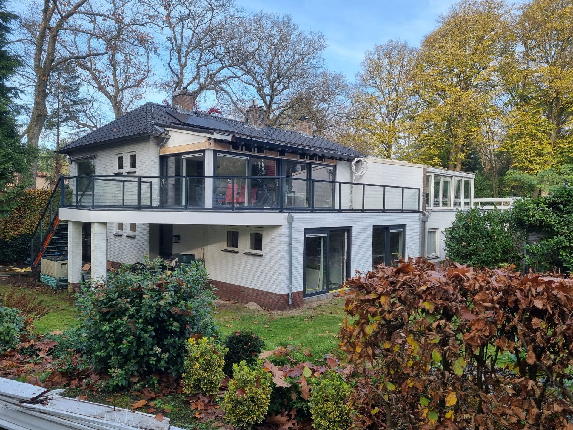 Twee verdiepingen wit huis met moderne ramen. Verbouwing en aanbouw renovatie.