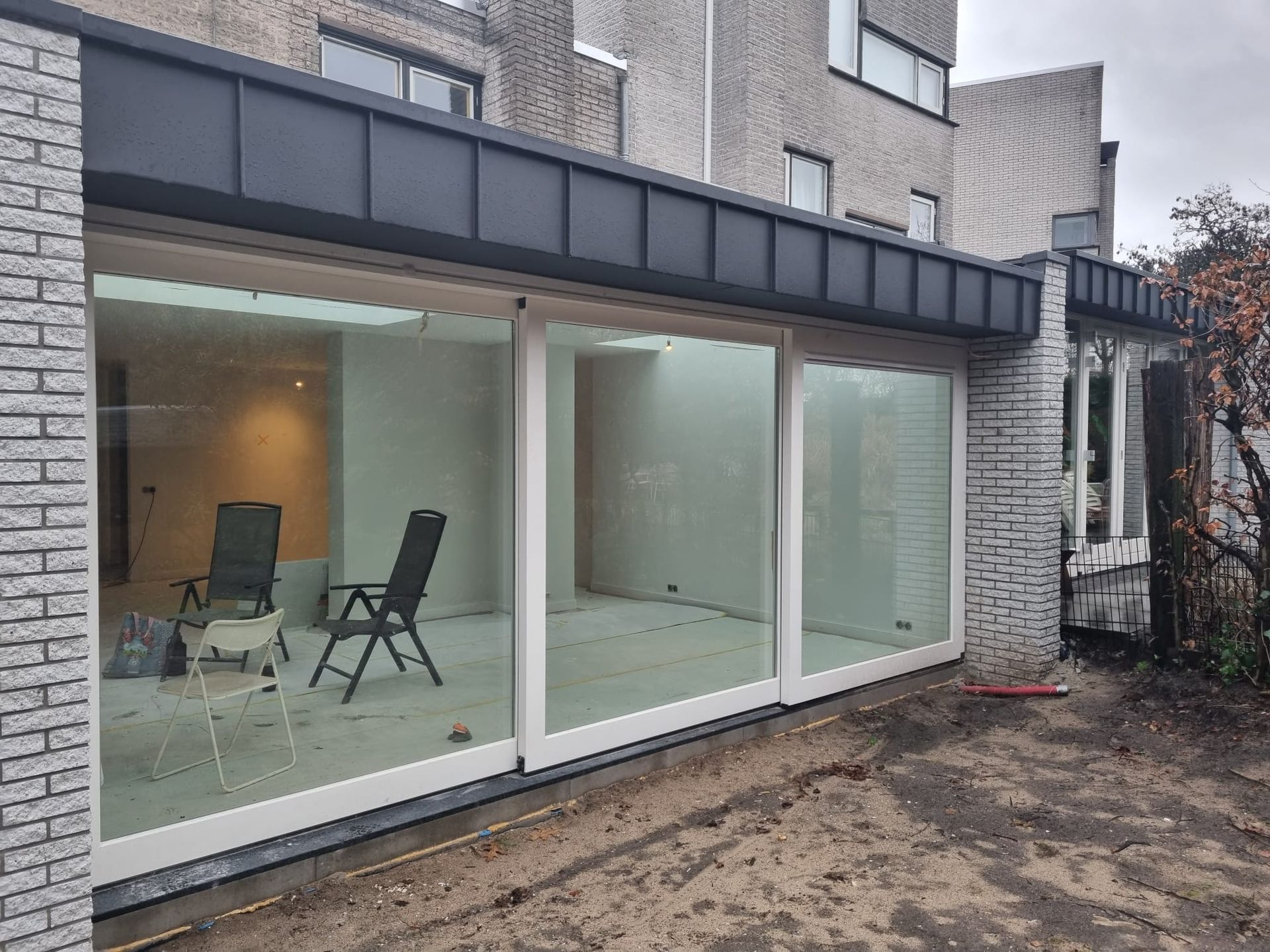 Woonkamer eetkamer na verbouwing met grote glazen wanden - huisrenovatie