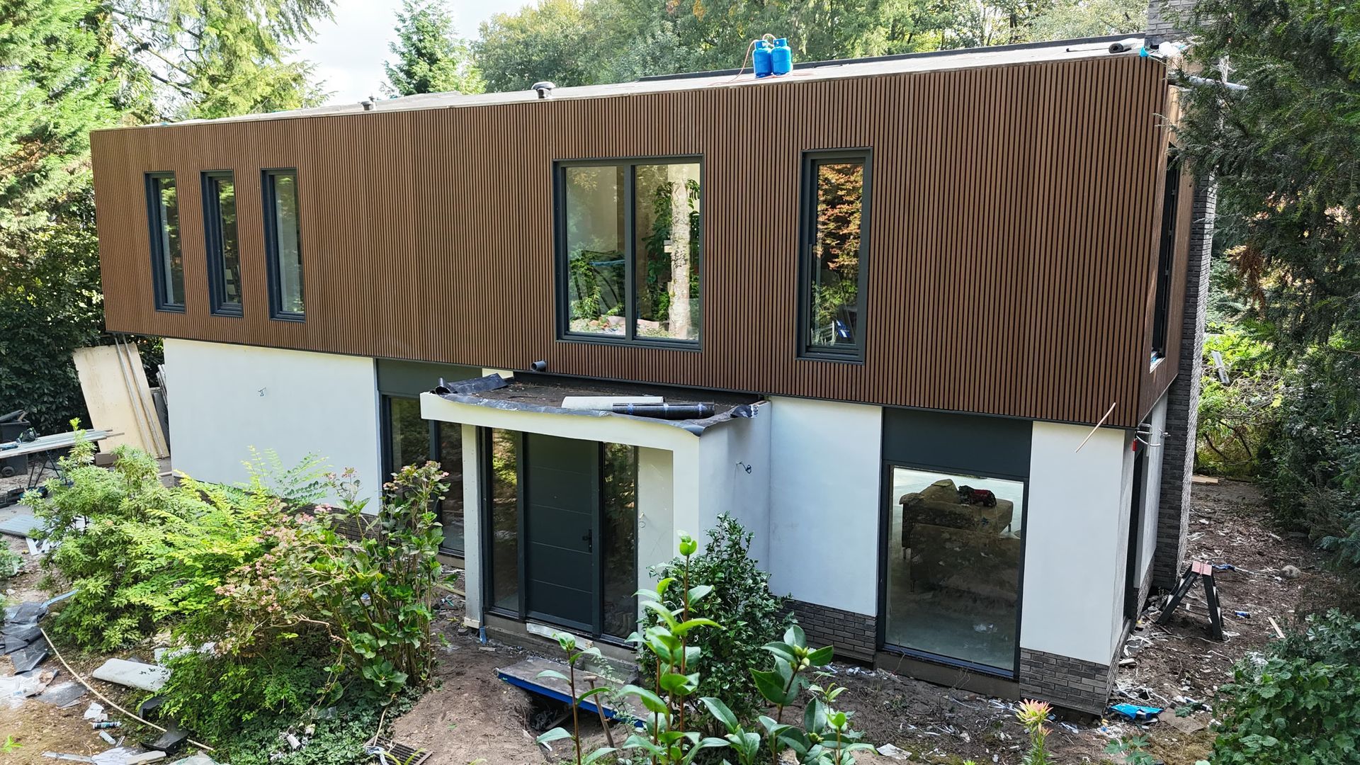 Gerenoveerde baksteenhuis donkere glazen aanbouw houten details. Verbouwing woning moderne uitbouw.
