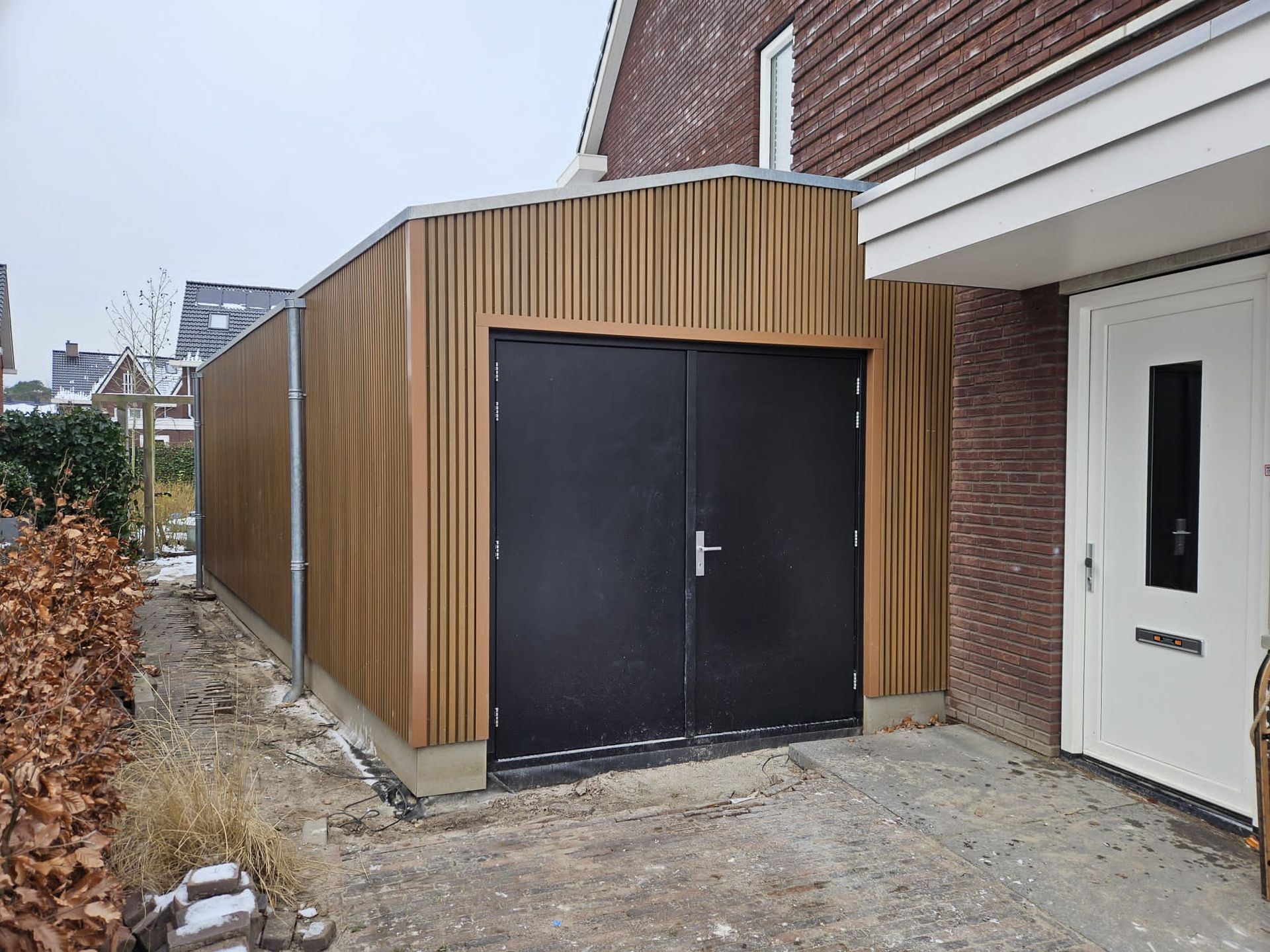Houten garage aanbouw met donkere deuren. Renovatie werkzaamheden.