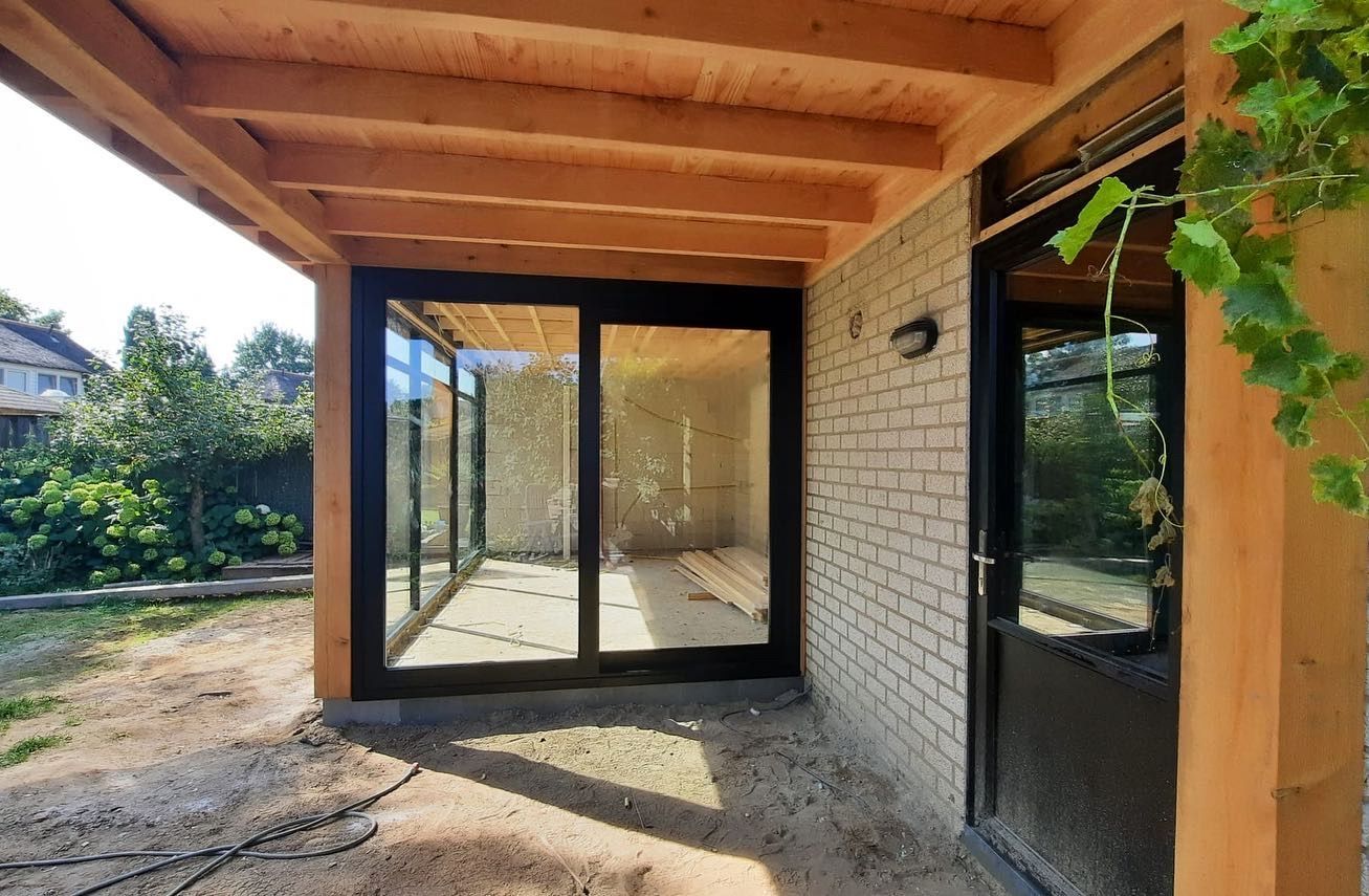 Aanbouw met glaswanden en deuren. Verandaverbouwing en aanbouwrenovatie modern.