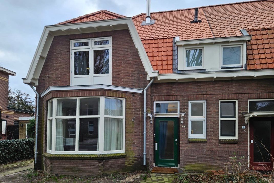 Bakstenen huis voorgevel. Witte ramen en rode dak. Traditionele woning renovatie.