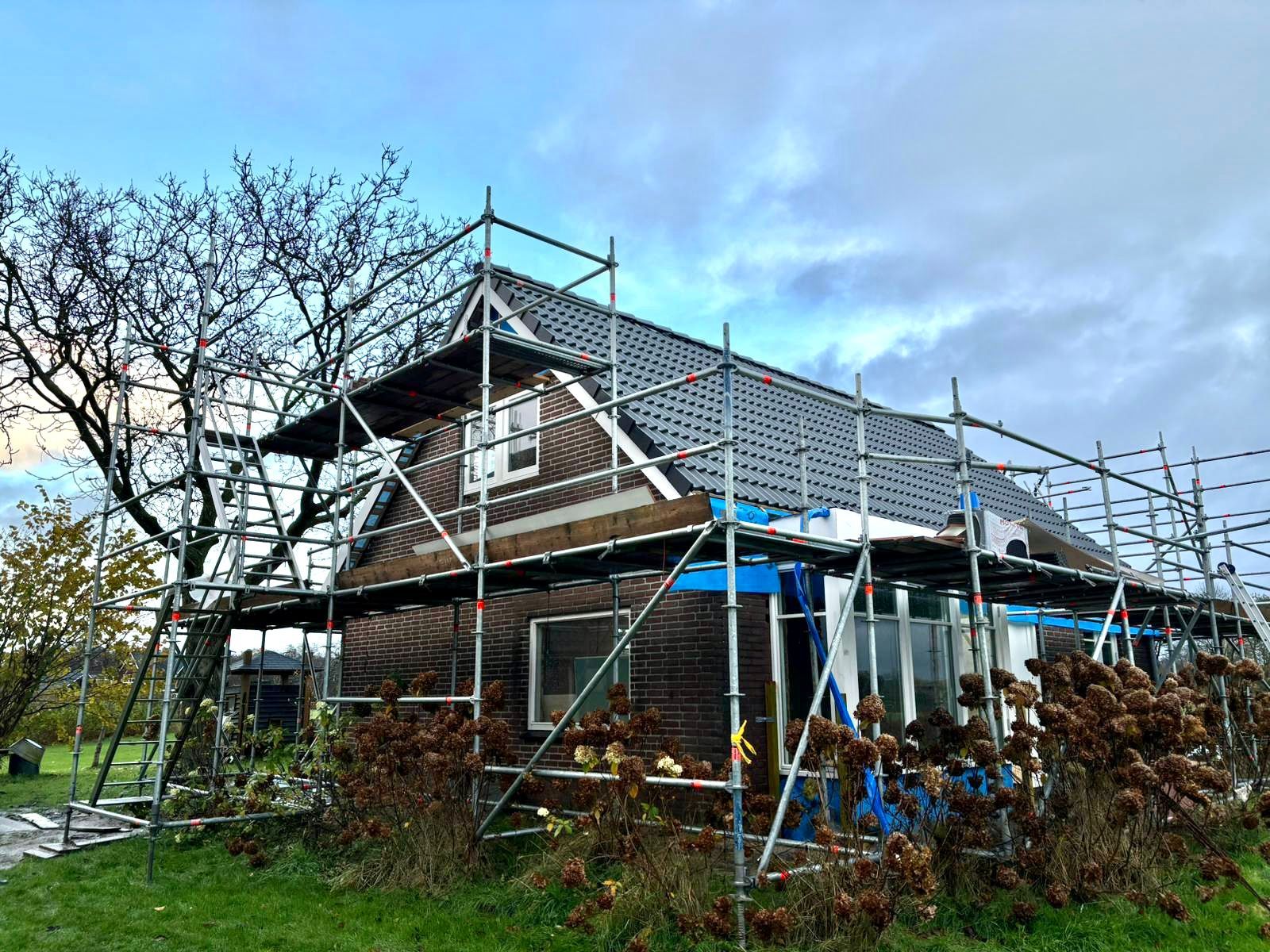 Bakstenen huis verbouwing met bouwsteiger rondom. Woningrenovatie en bouwsteiger werk.
