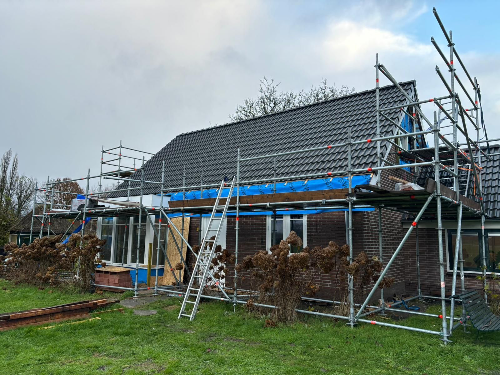 Woning verbouwing met donker dak en beschermmateriaal. Dakrenovatie en woningverbouwing.