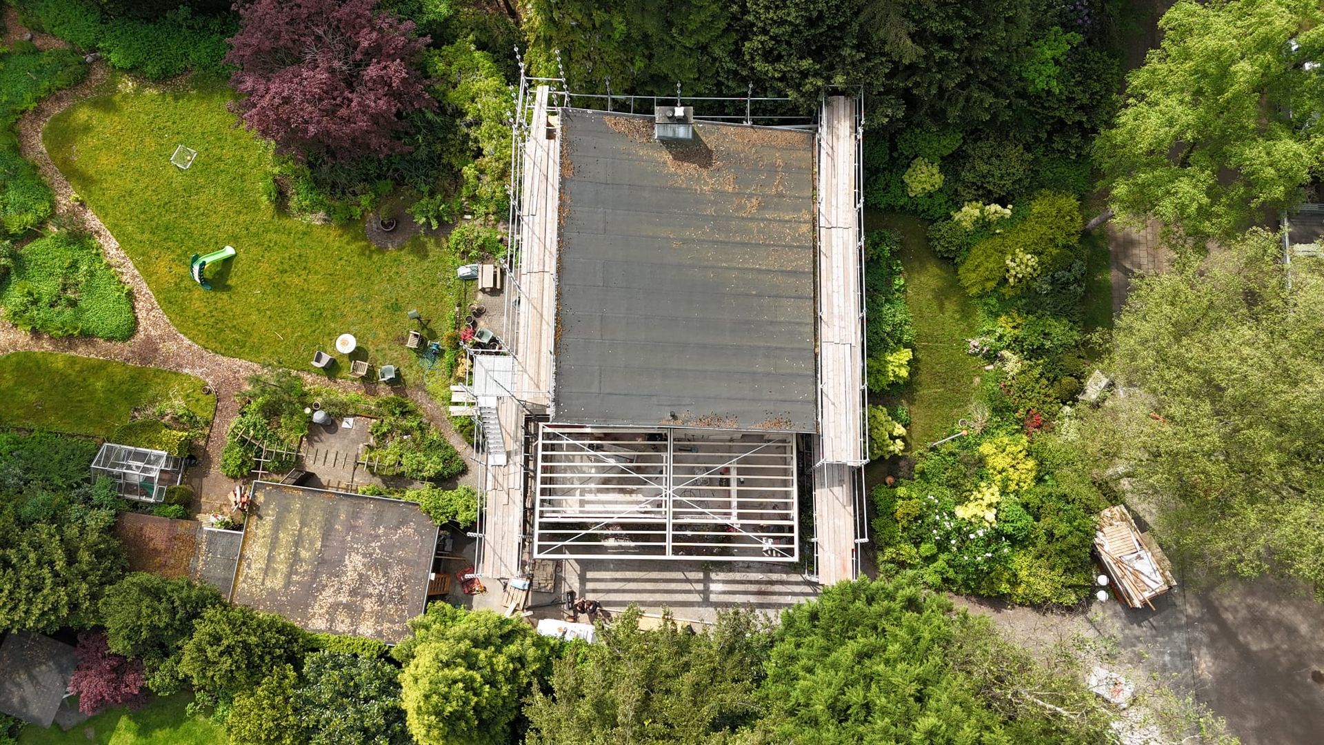 Luchtfoto groene tuin houten terras aanbouw. Aannemer tuinuitbouw terrasverharding.