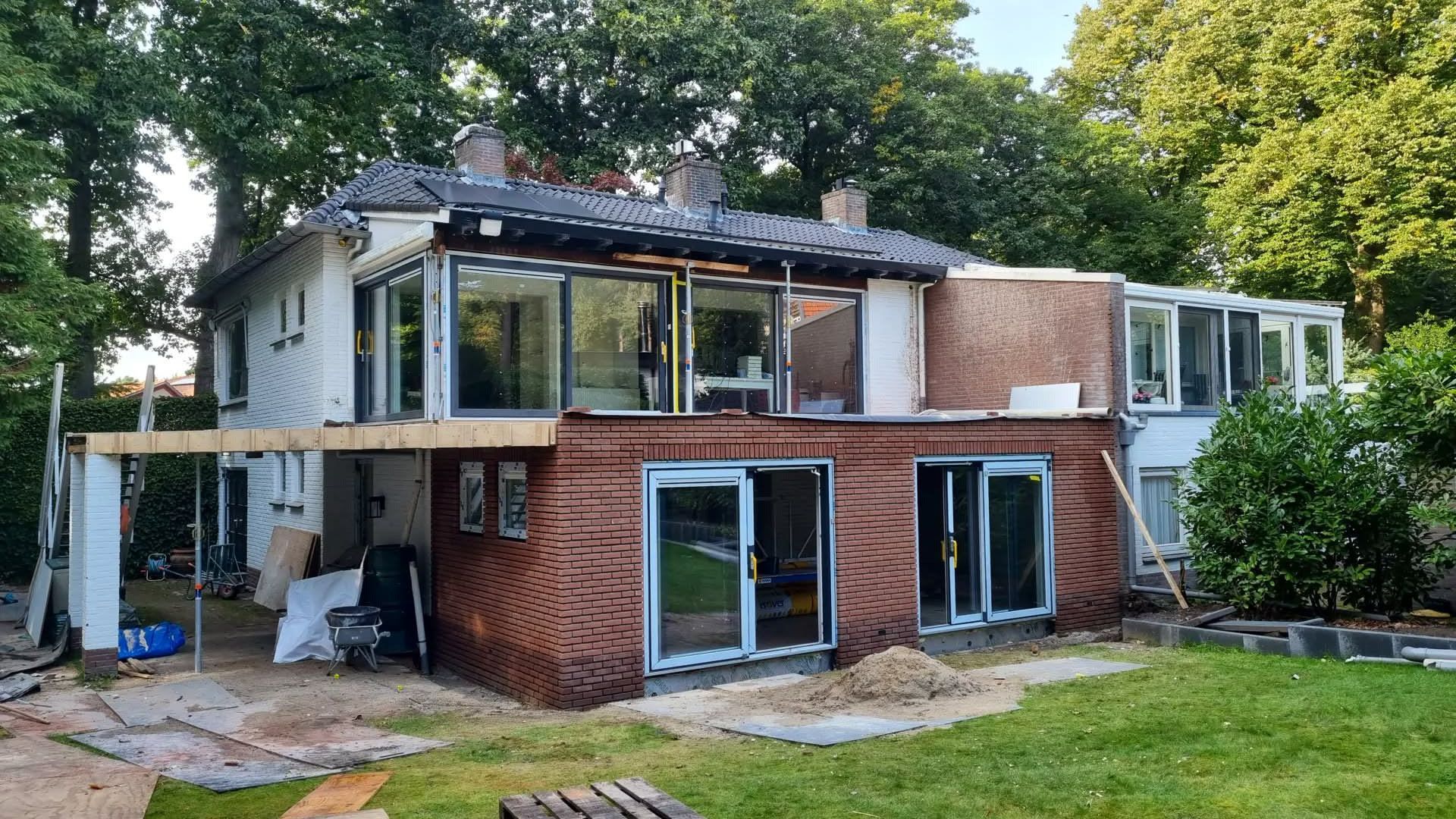 Modern huis met bakstenen aanbouw en terras. Huisrenovatie en verbouwing aanbouw.