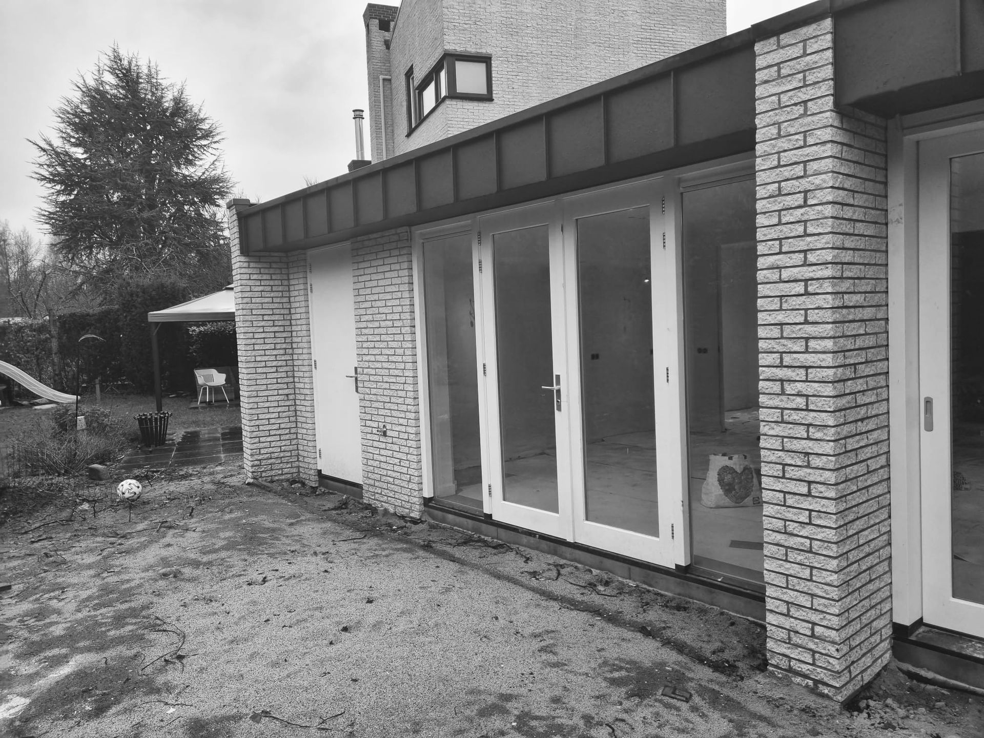 Aanbouw aan bakstenen huis. Woninguitbouw en gevelrenovatie.