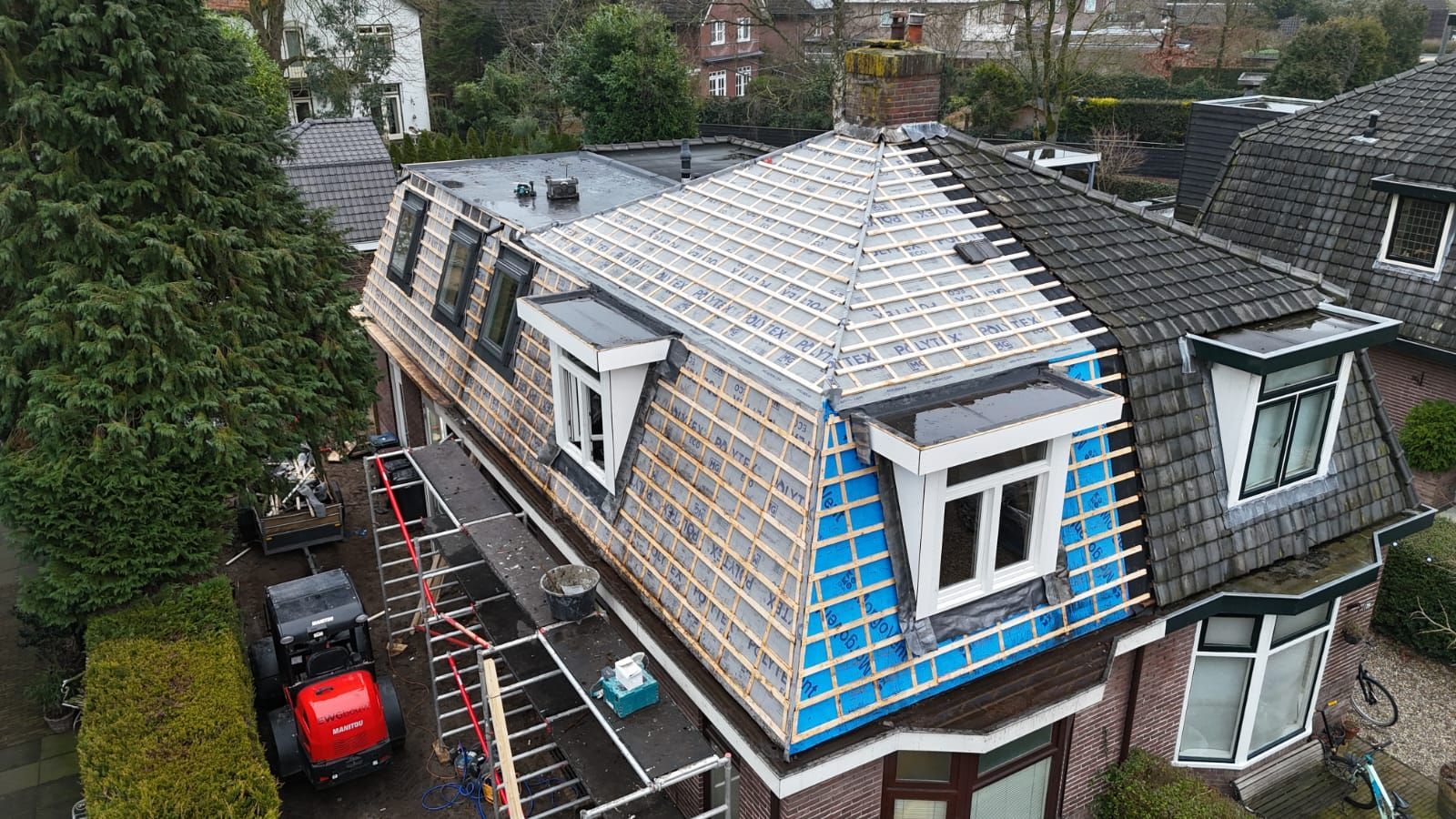 Dakrenovatie in voorbereiding. Blauw onderdak en steiger. Dakwerk aannemer in aanbouw.