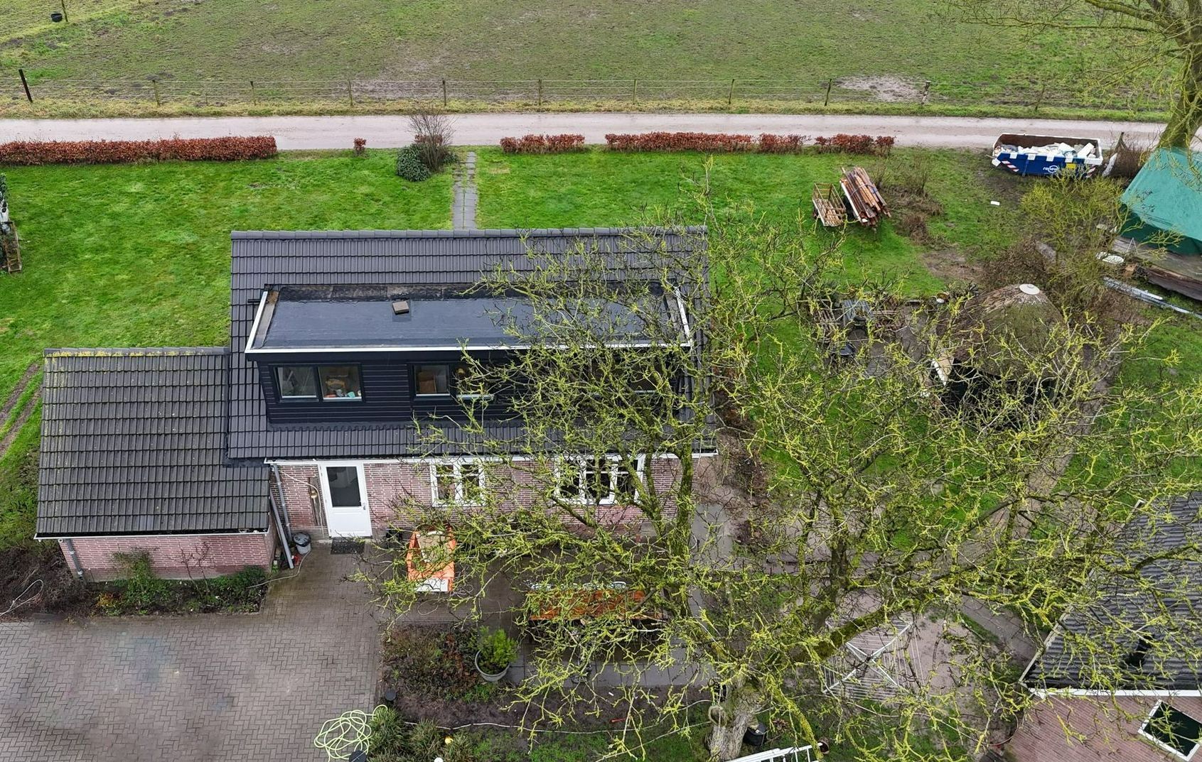 Luchtfoto gerenoveerde woning met donker dak. Woningrenovatie en dakwerk afgewerkt.