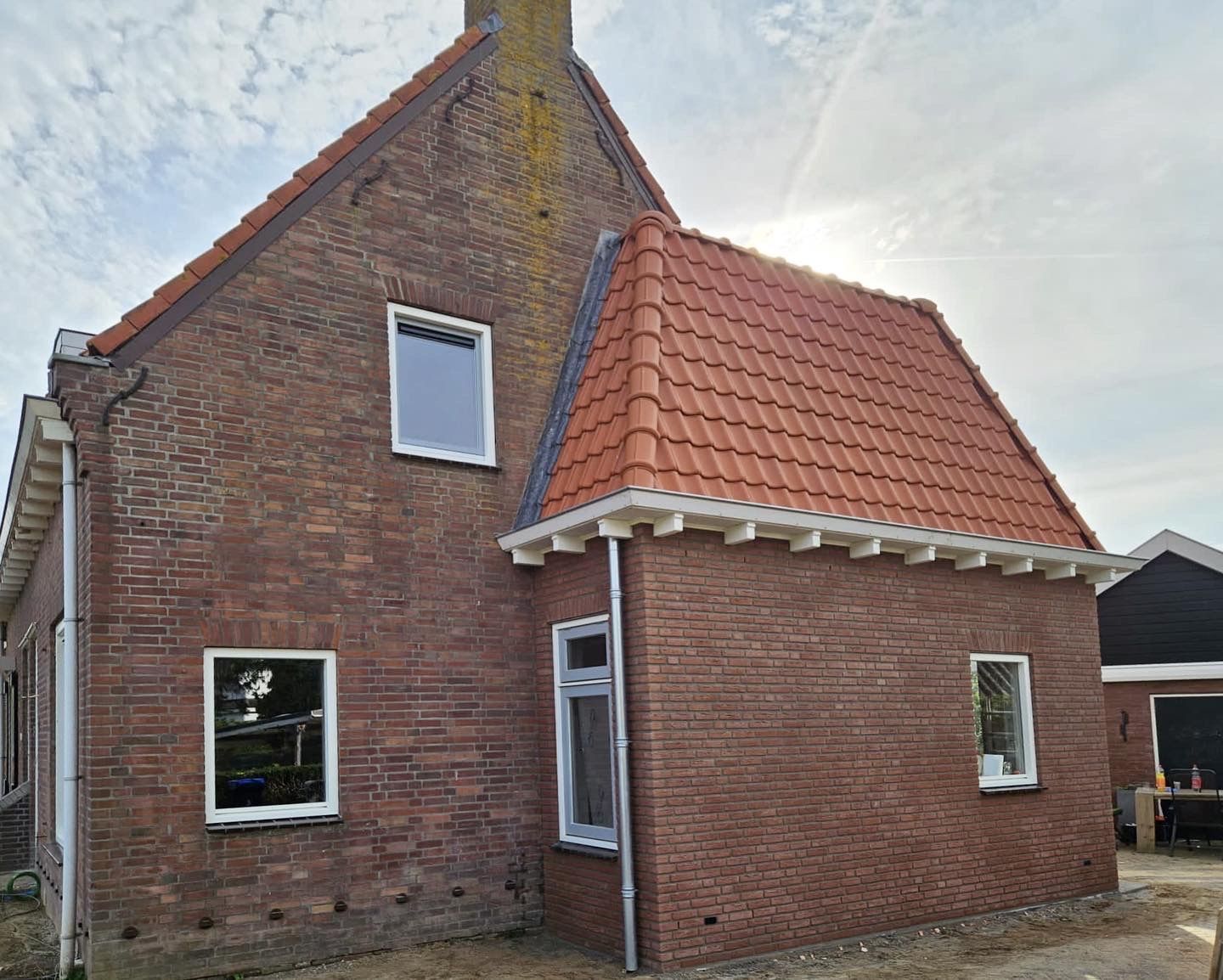 Gerenoveerde bakstenen woning met rood dak. verbouwing voorgevel.