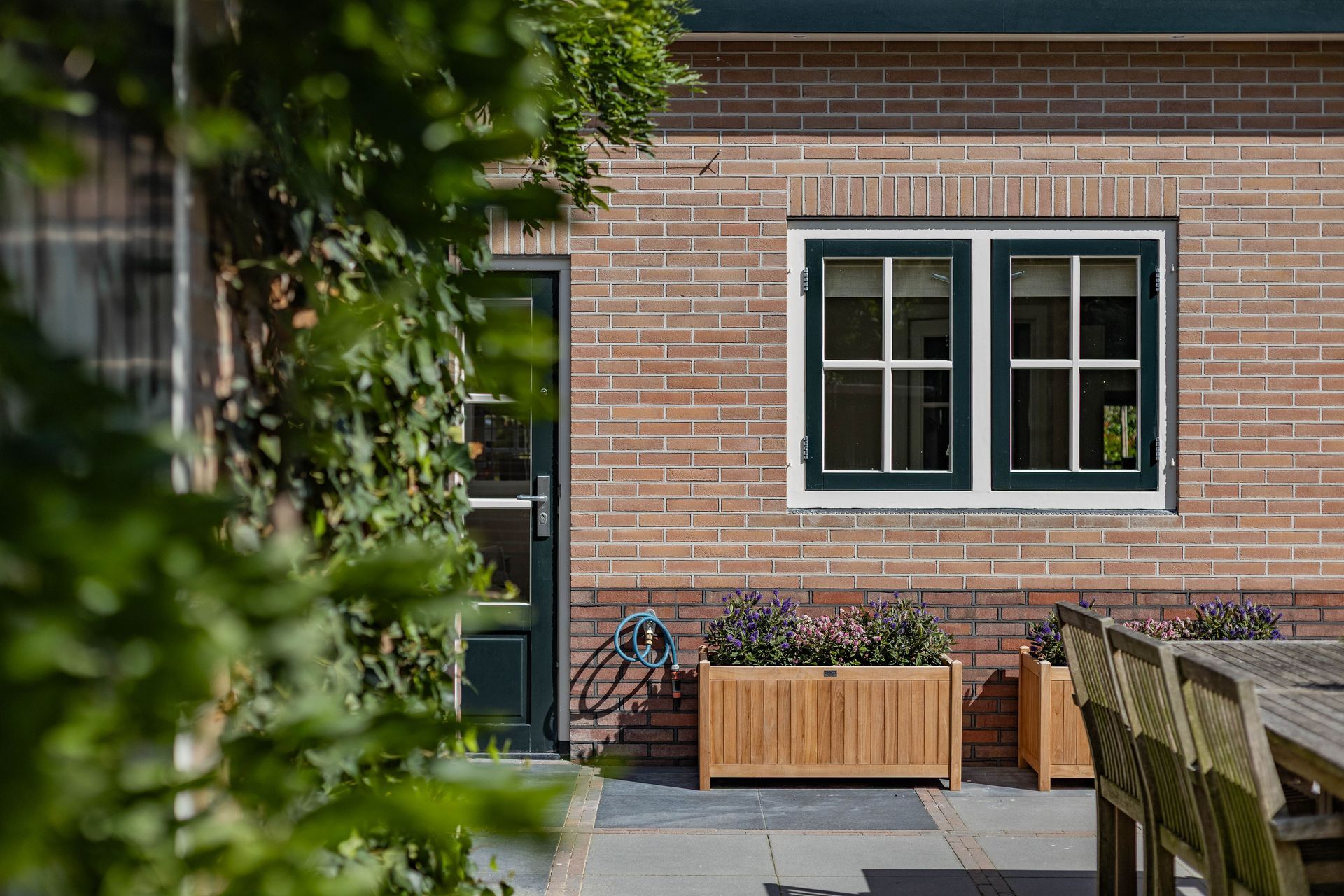 Bakstenen voorgevel met ramen en terras. Huisrenovatie en verbouwing van woonhuis door aannemer.