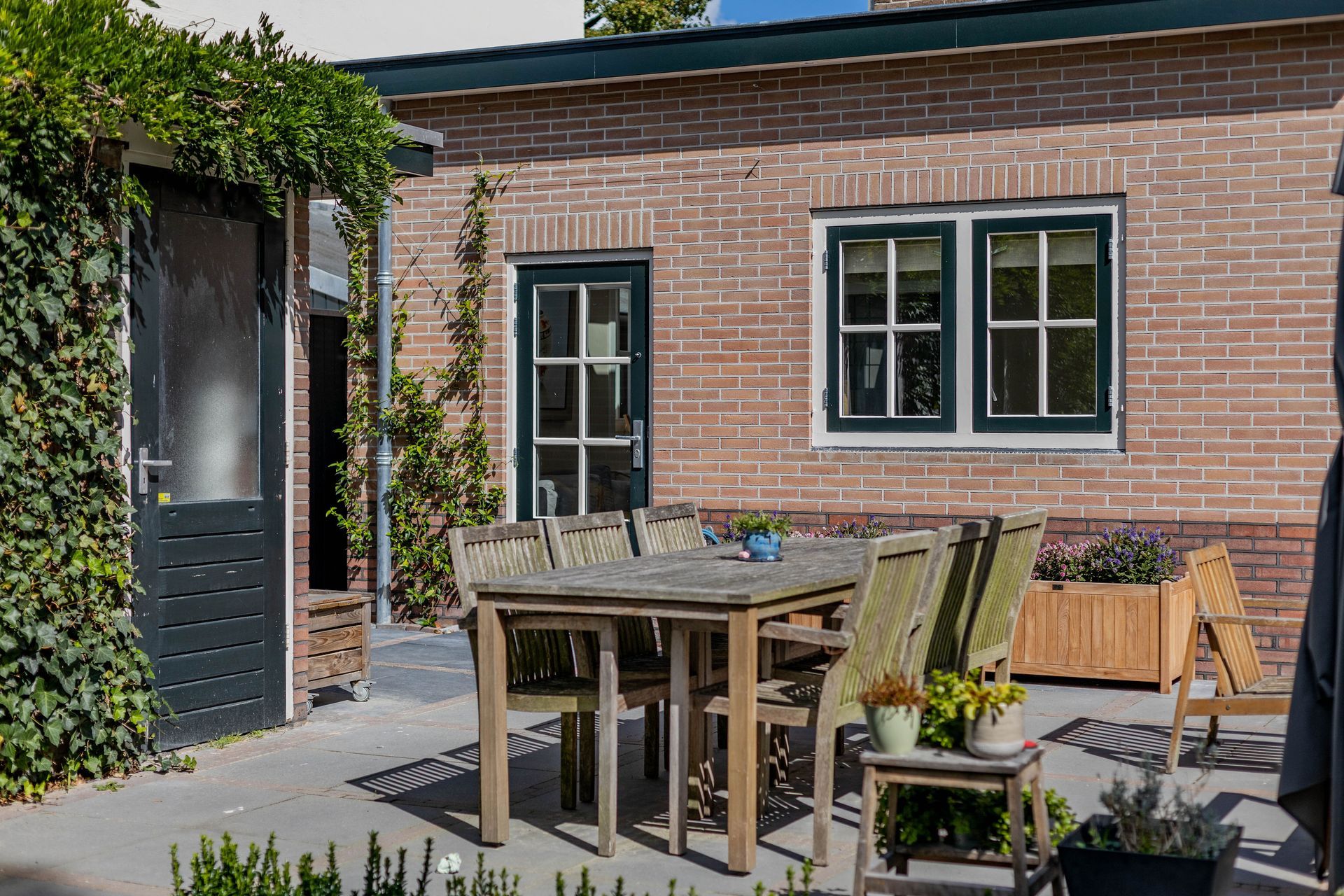 Bakstenen woning met houten terras voor tuinverbouwing. Renovatie en aanbouw van woonruimte.