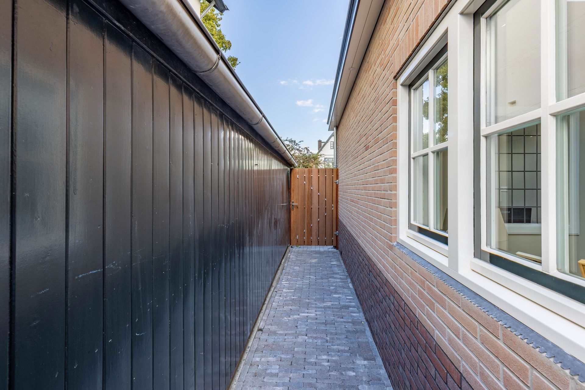 Smalle gang met donkere wand en bakstenen bouw. Uitbouw en aanbouw renovatie.