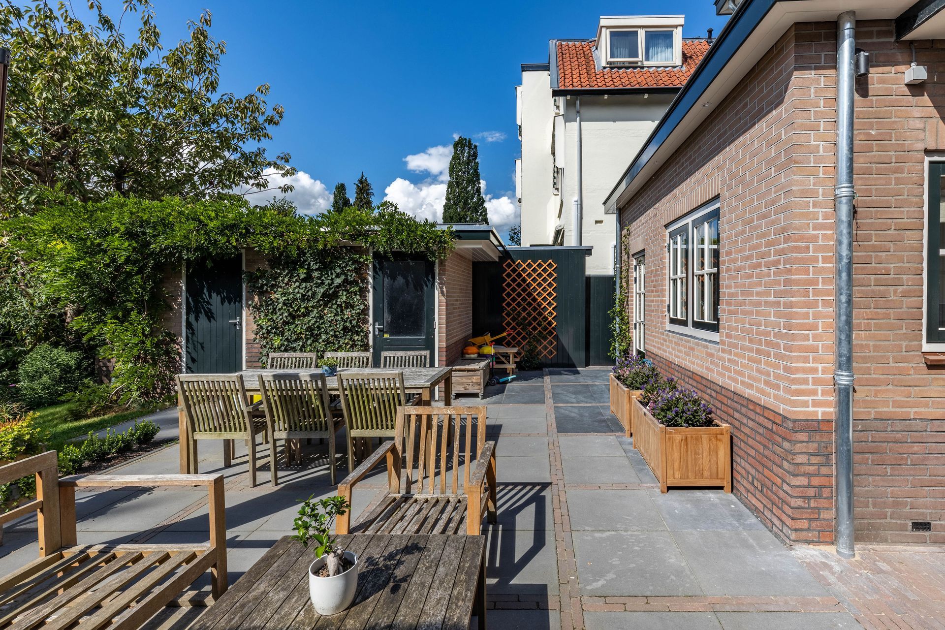 Terras met houten meubels en pergola afdak. Tuinverbouwing en terrasontwerp door aannemer.