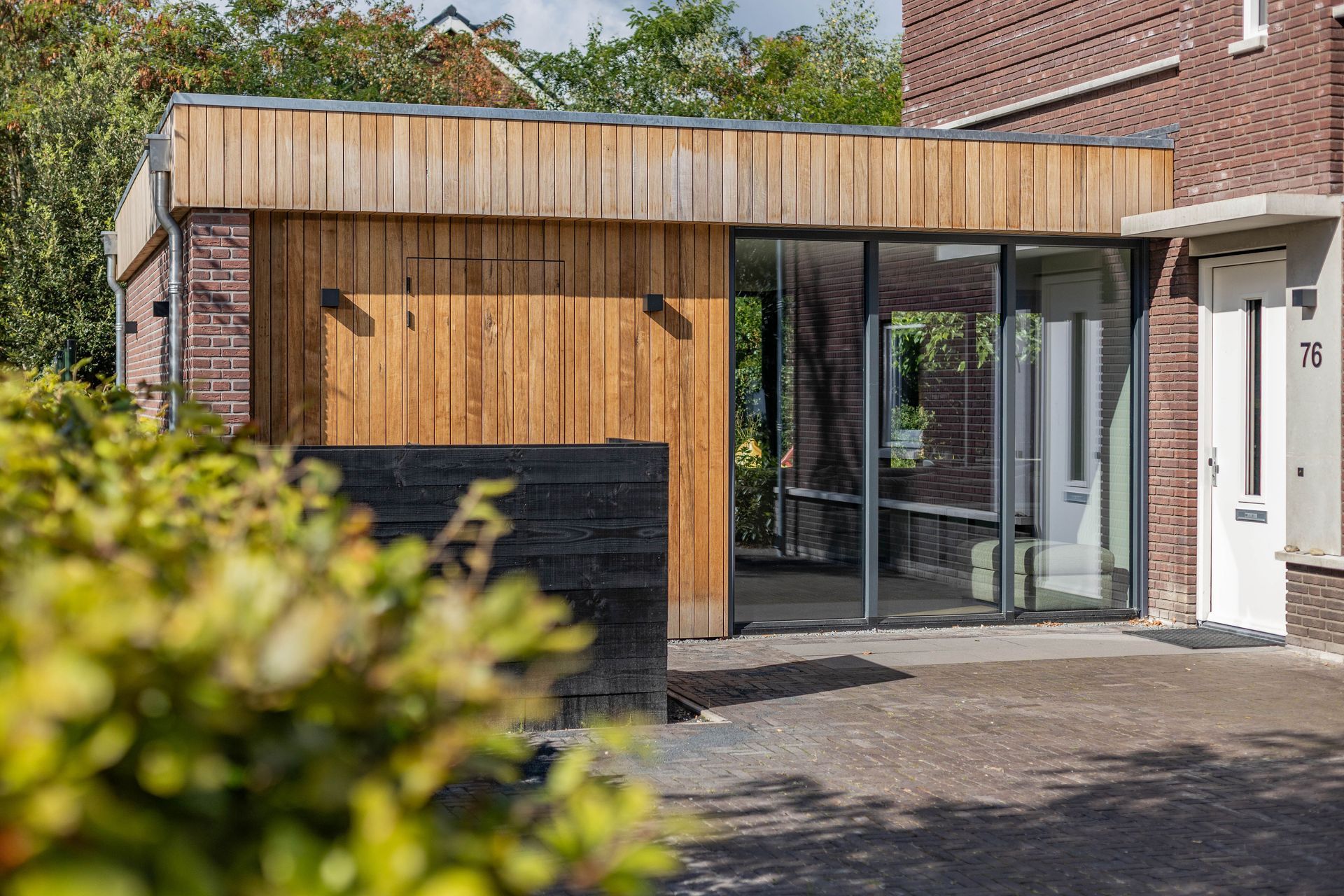 Gerenoveerde woning. Houten aanbouw met donkere accenten.