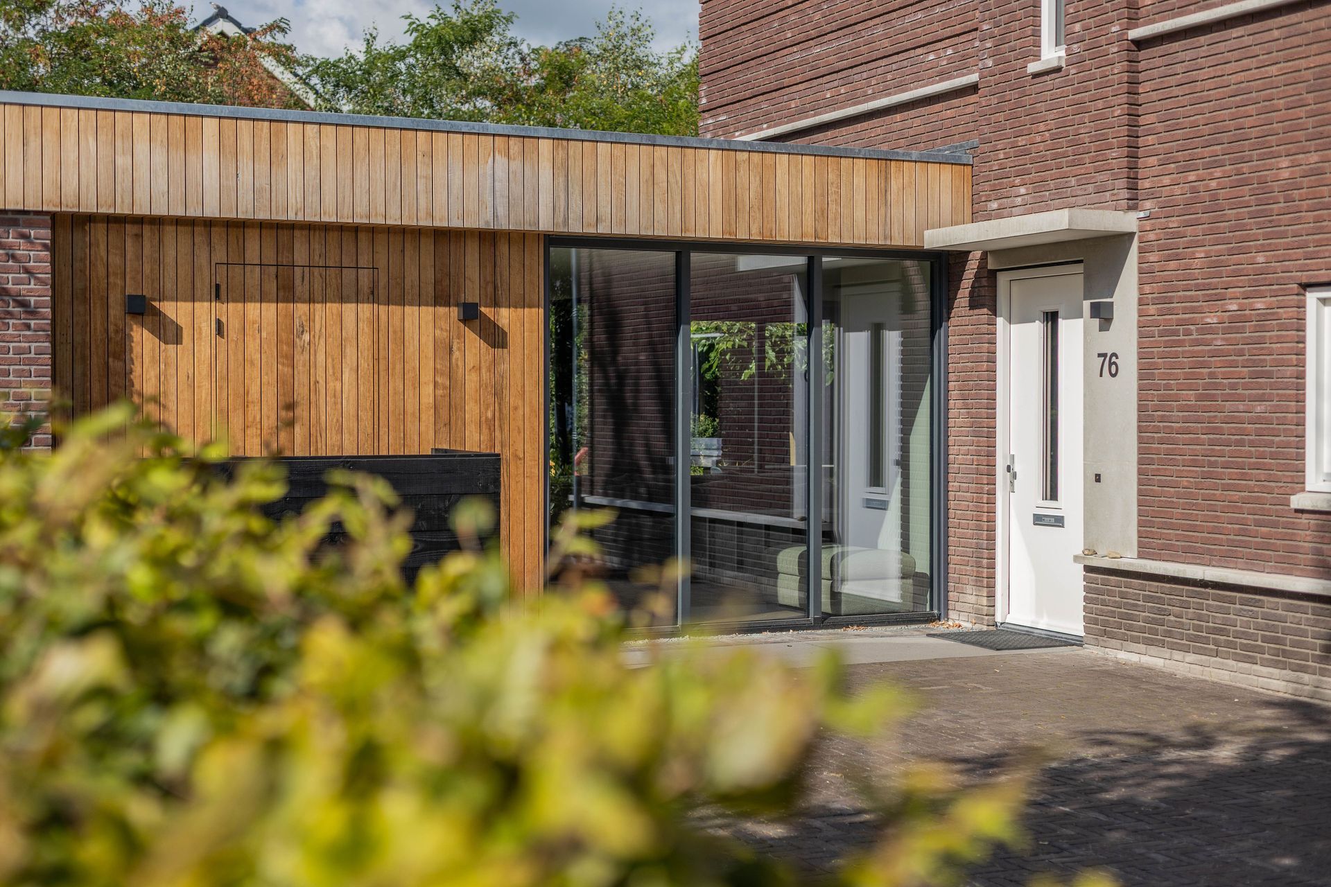 Houten aanbouw schuifdeuren glas. Moderne integratie bakstenen. Verbouwing uitbouw.