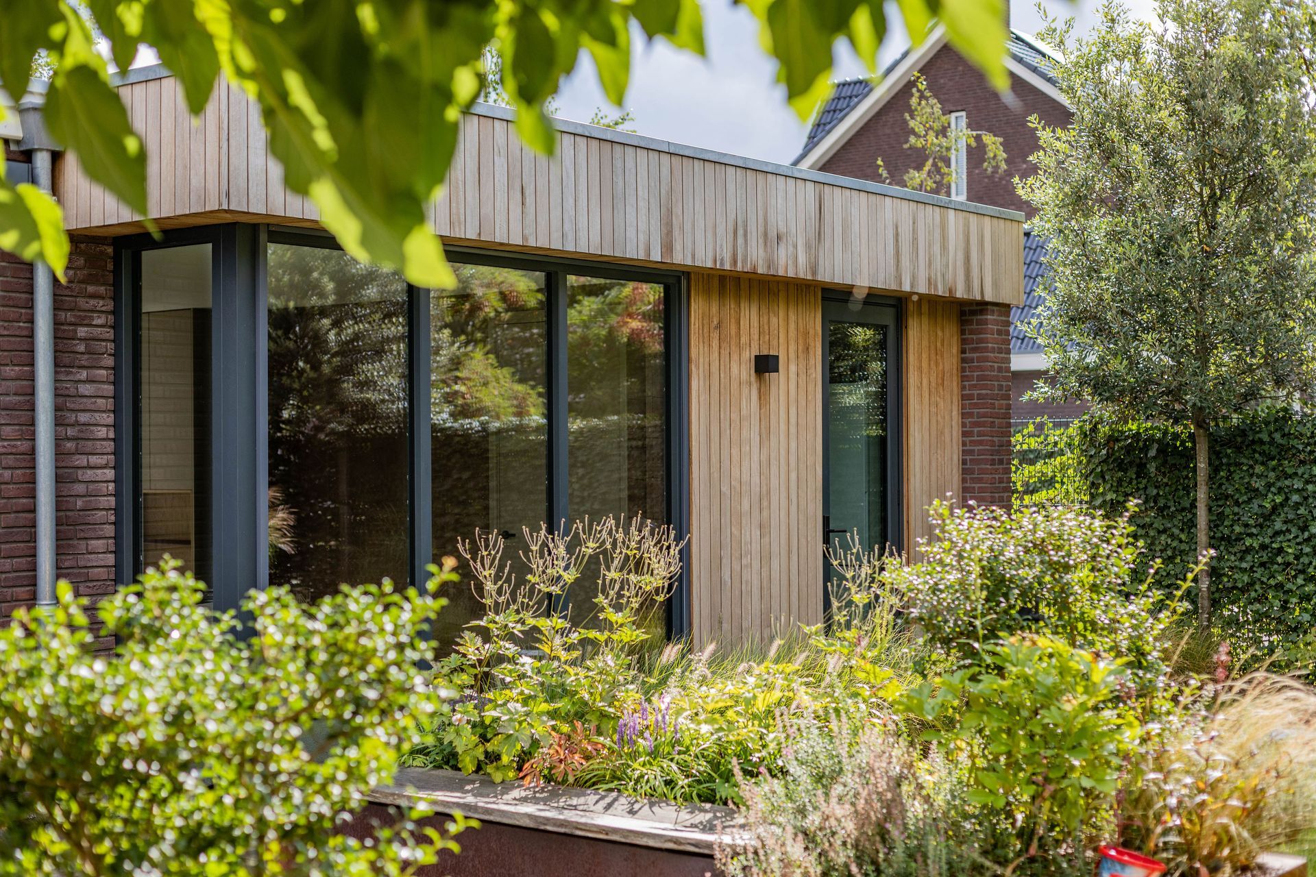 Aanbouw met houten gevelbekleding en glaspartijen
