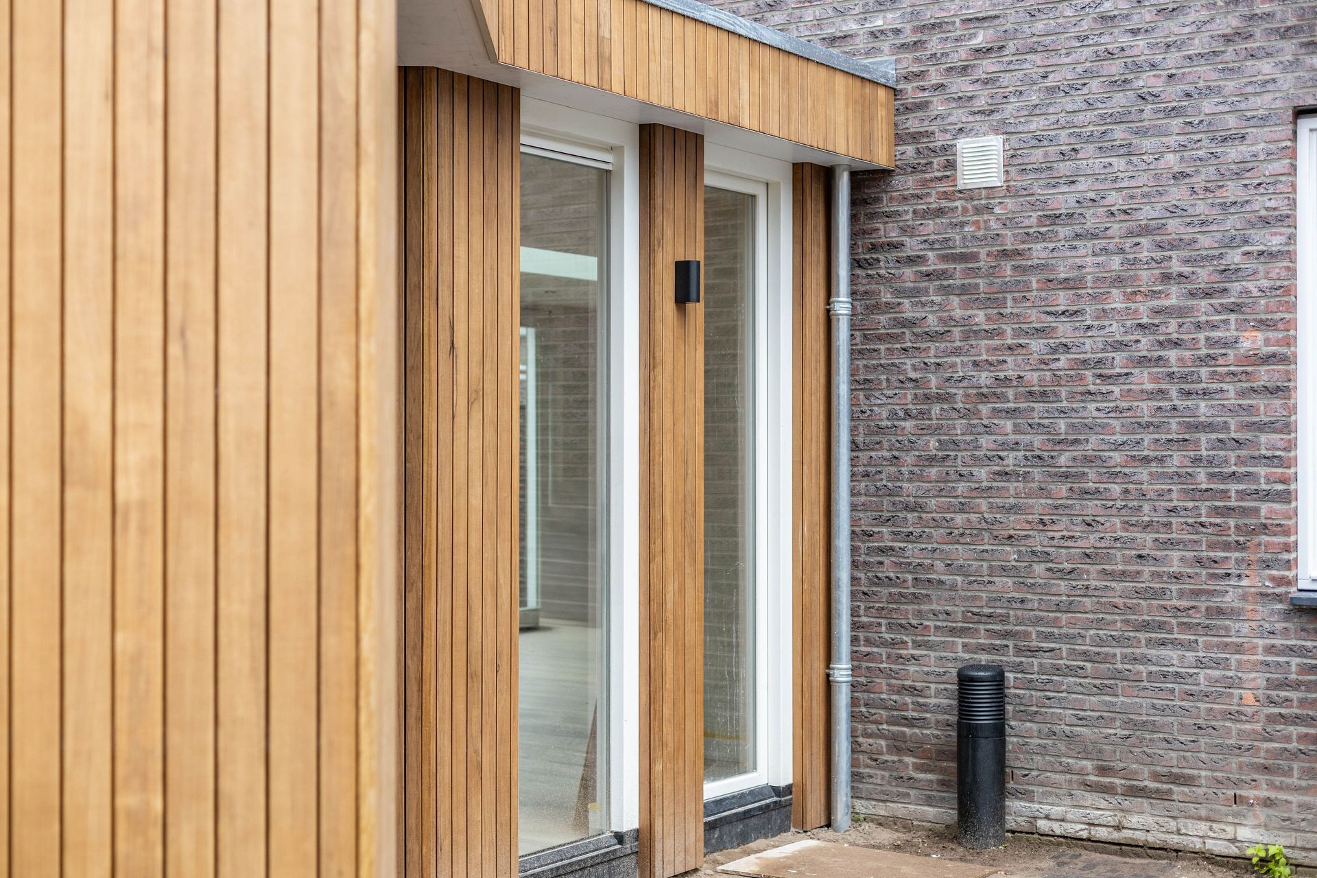 Houten aanbouw bekleding. Witte deuropening glas. Verbouwing interieur.