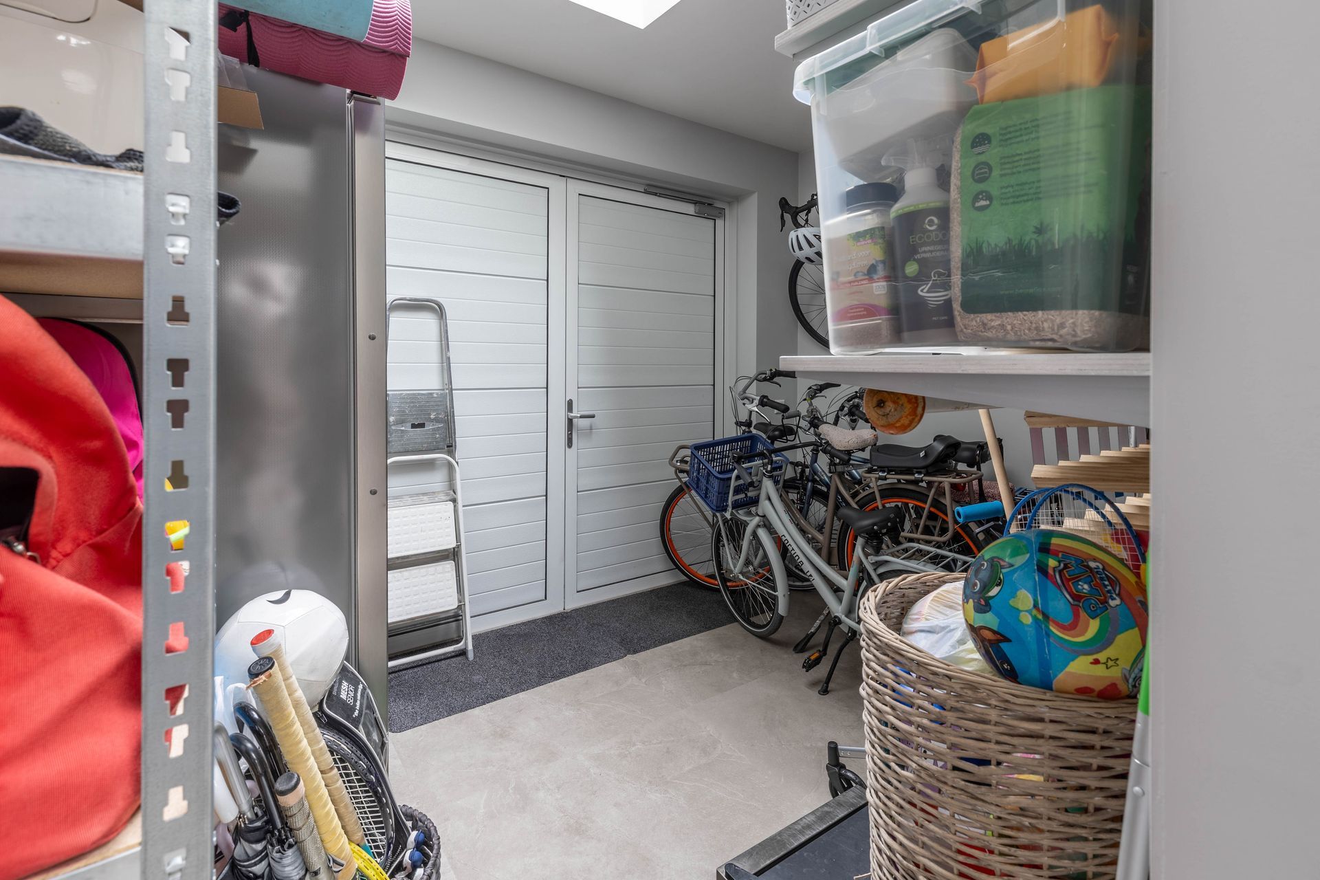 Garageberging met fietsen, opbergbakken en een witte dubbele deur.